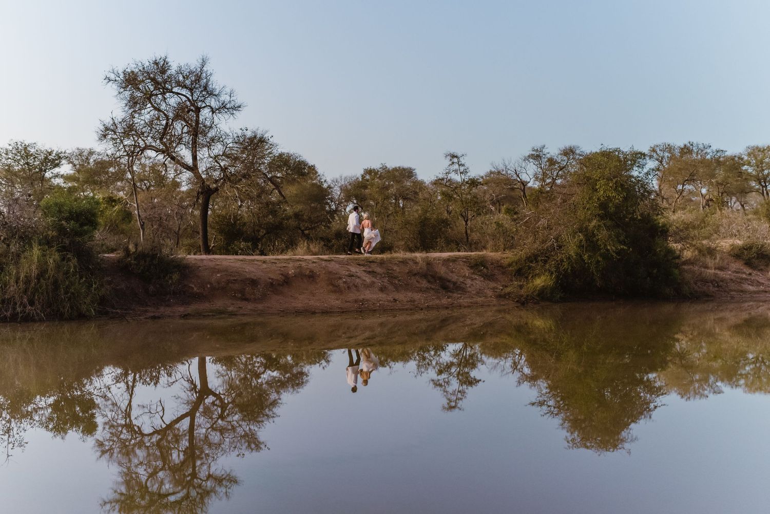 Panoramic view of a coastal lagoon with trees reflecting in still water.