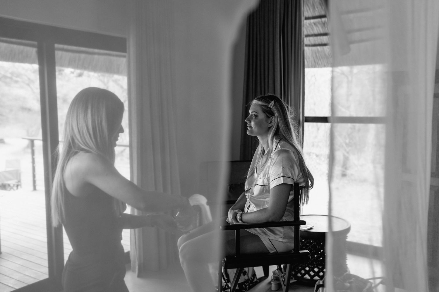 Sunlit interior room with white curtains and silhouettes of people getting ready.
