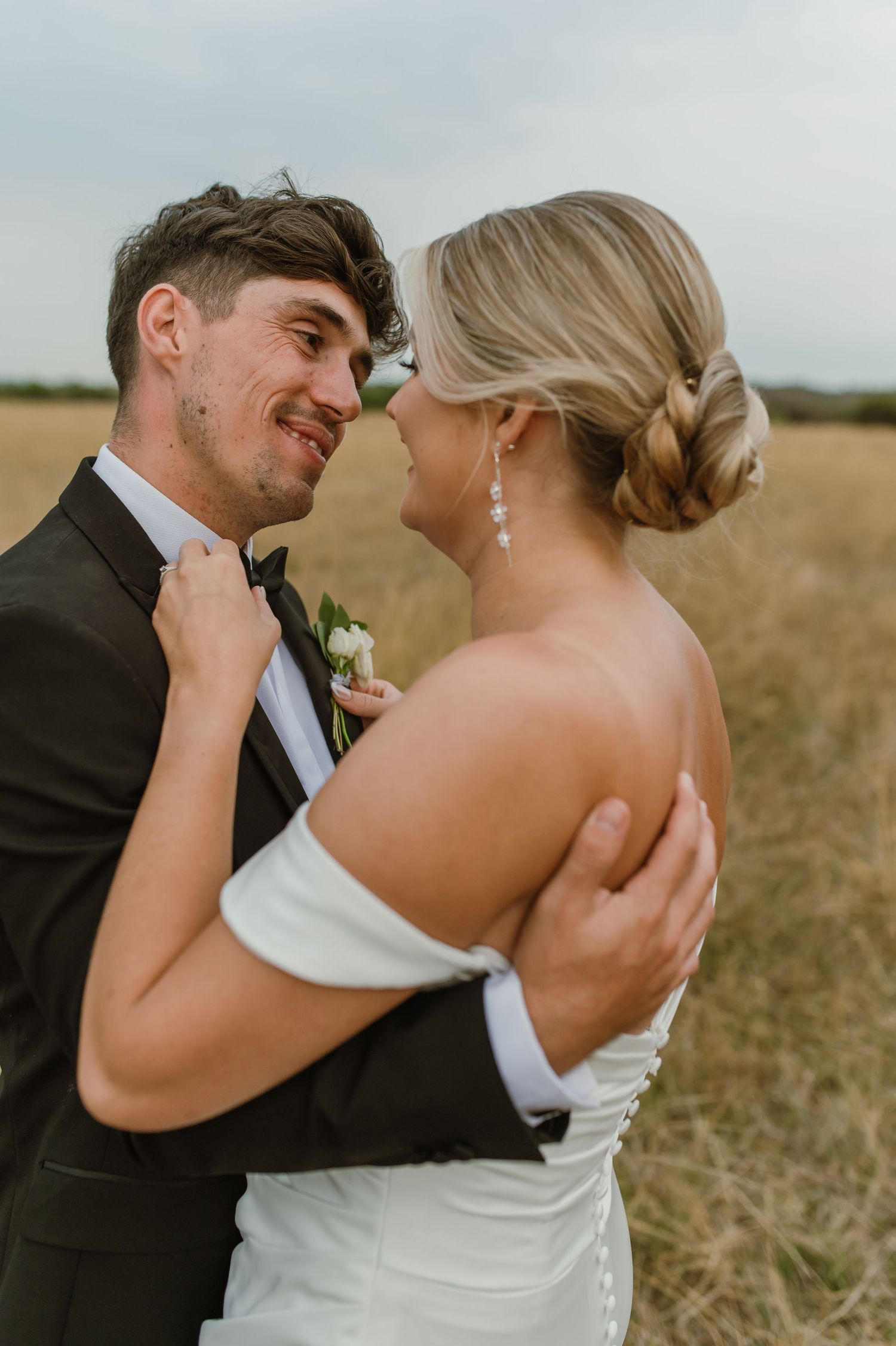 A romantic wedding photo series showing tender moments between a couple in formal attire in a field.