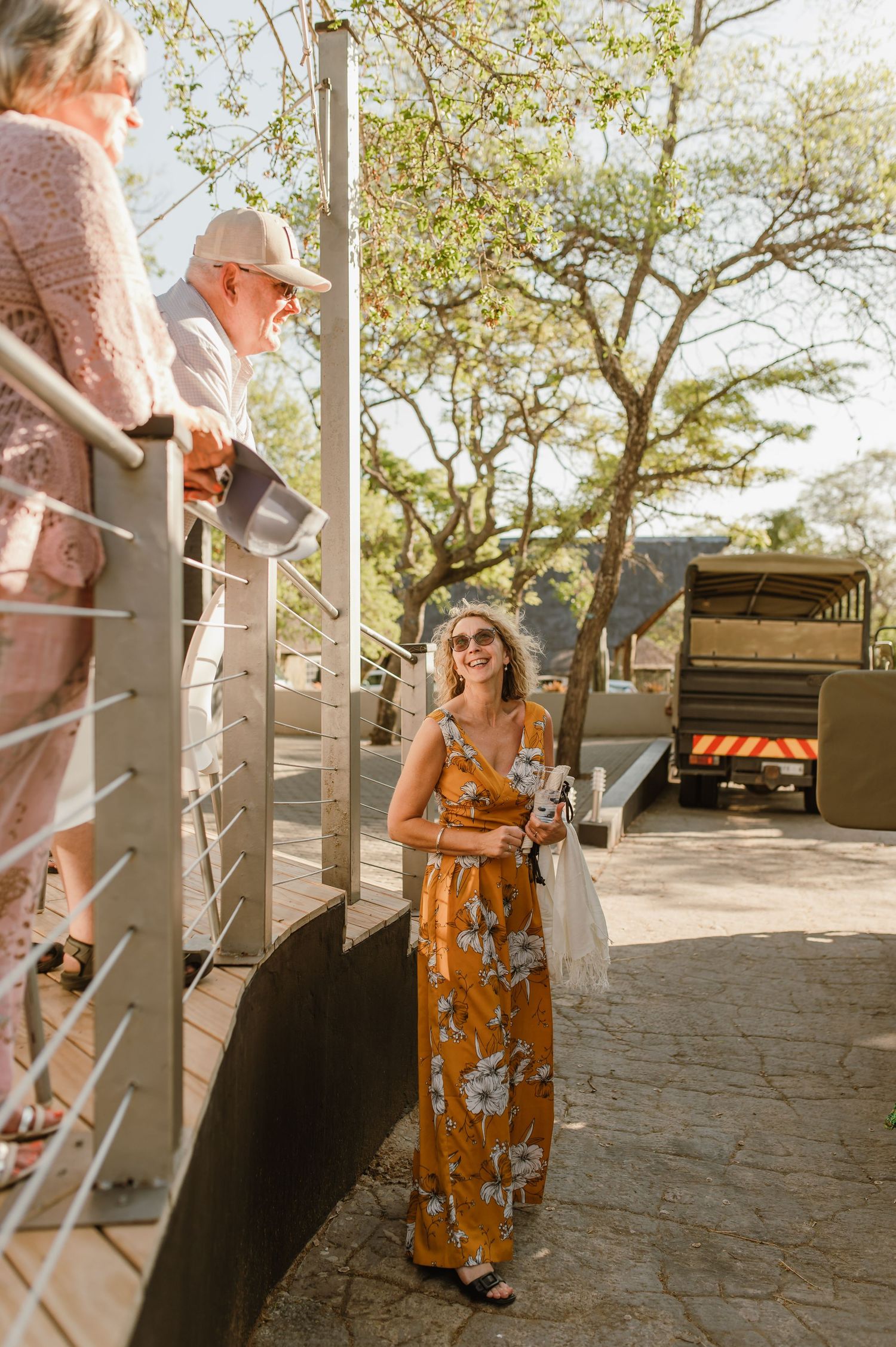 Guests enjoying a casual outdoor event under trees with stone patio flooring.