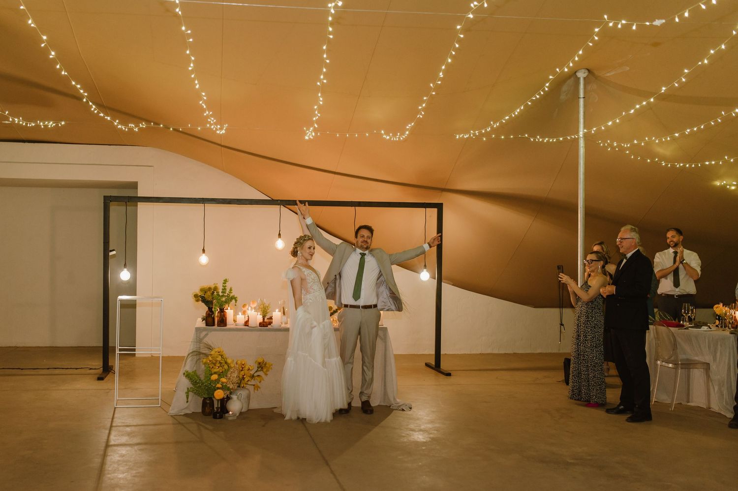 Panoramic view of wedding tent with string lights and dancing celebration.