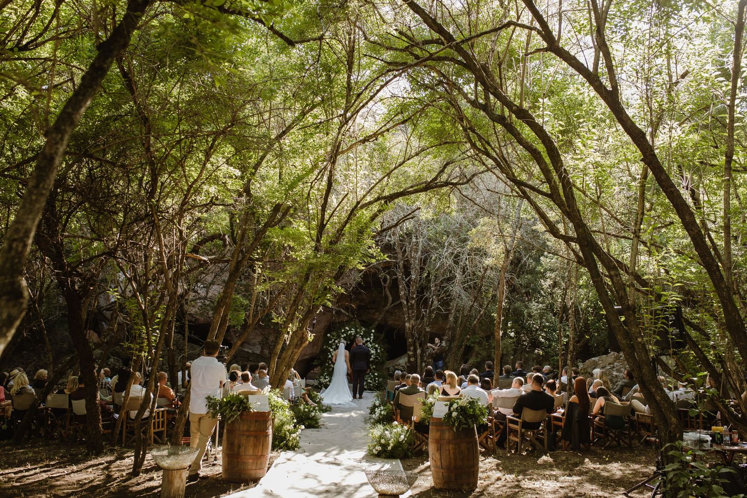 Natural forest wedding venue with trees creating a canopy over ceremony seating.