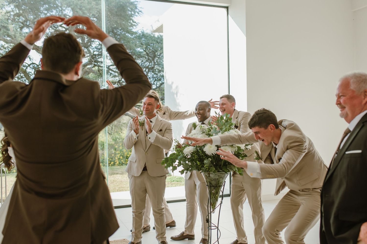 Wedding party members arranging floral decorations in bright indoor venue.