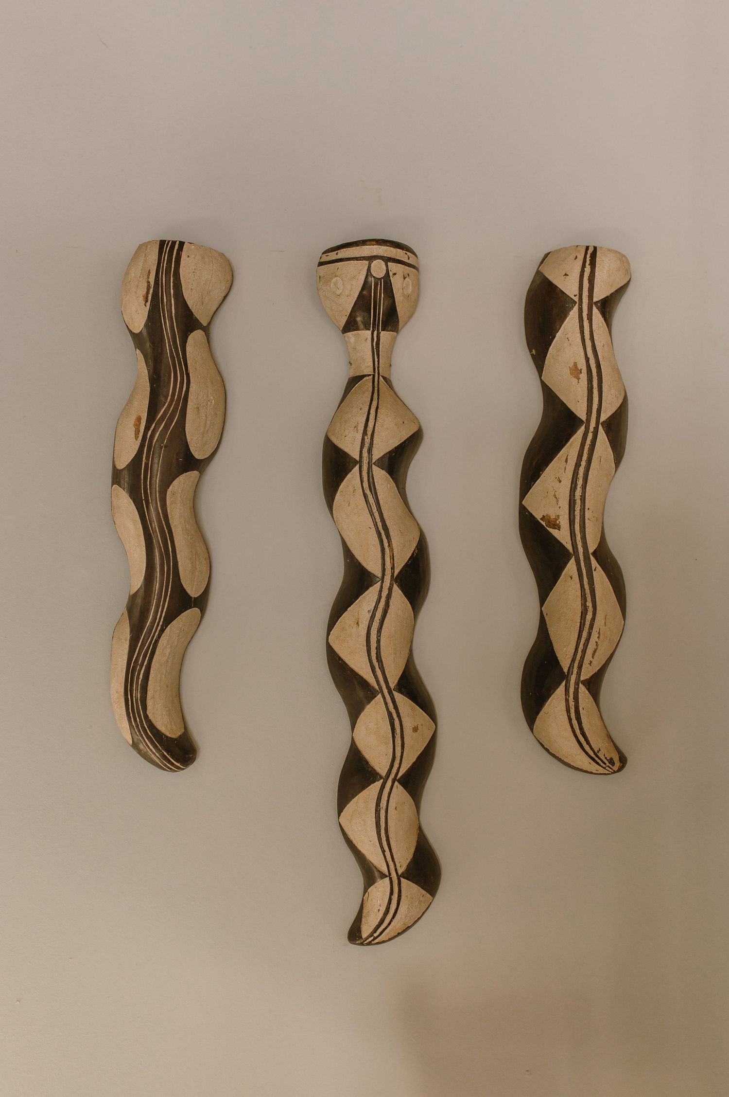 Abstract wall art featuring curved black and tan shapes in a repeating pattern.