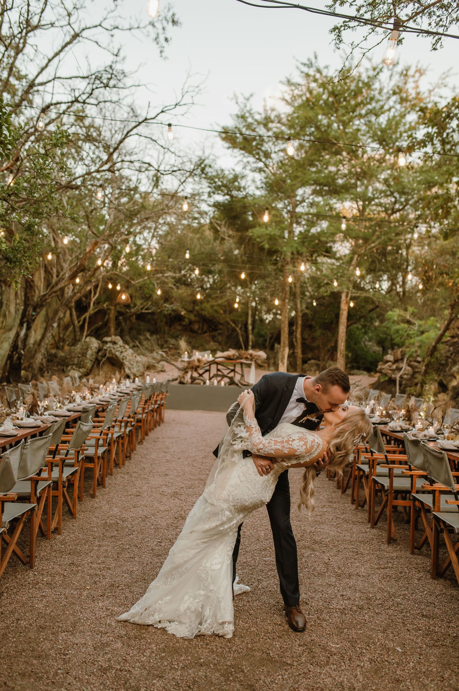A couple shares a romantic dip pose on their reception aisle under twinkling lights.