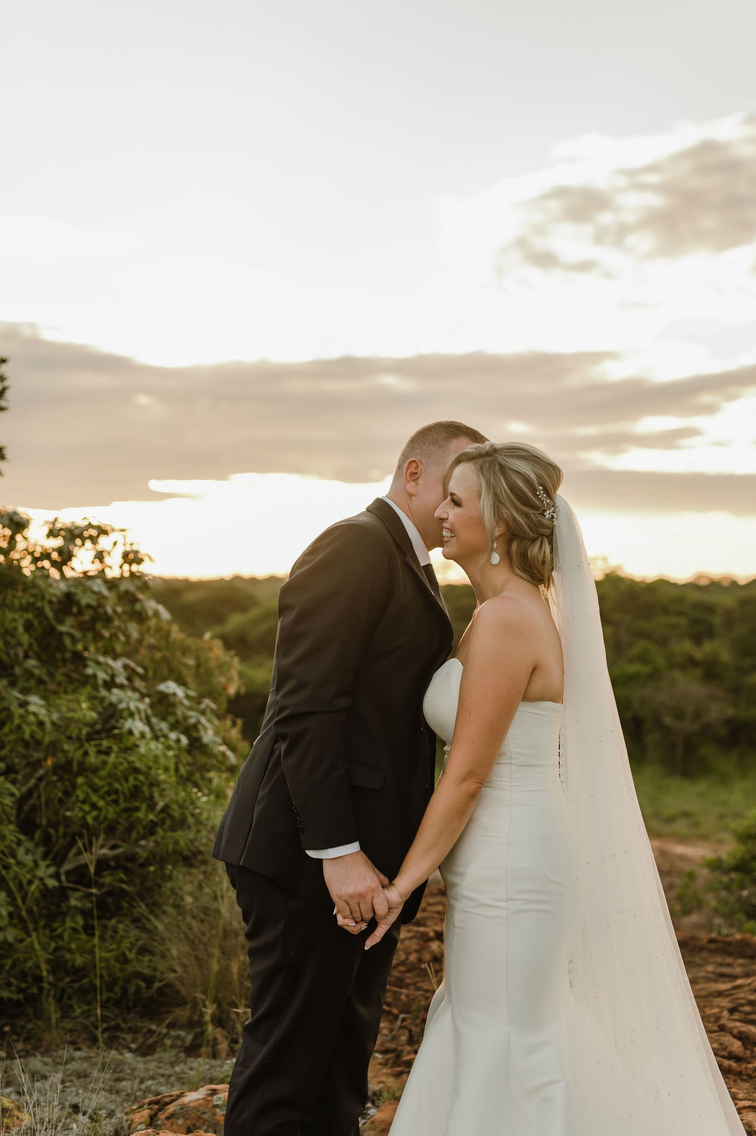A romantic sunset wedding portrait shows a couple embracing on rocky terrain with golden light in the background.