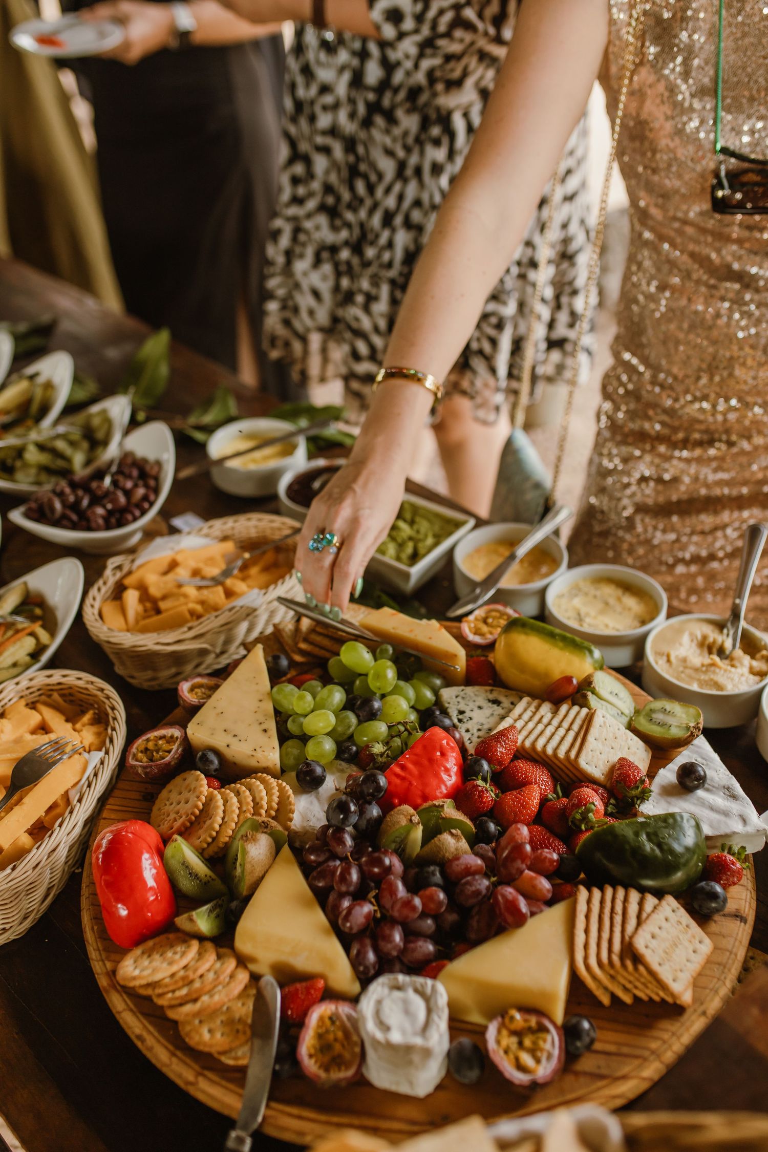 An elegant charcuterie board with fresh fruits, cheeses, crackers and grapes displayed at a gathering.