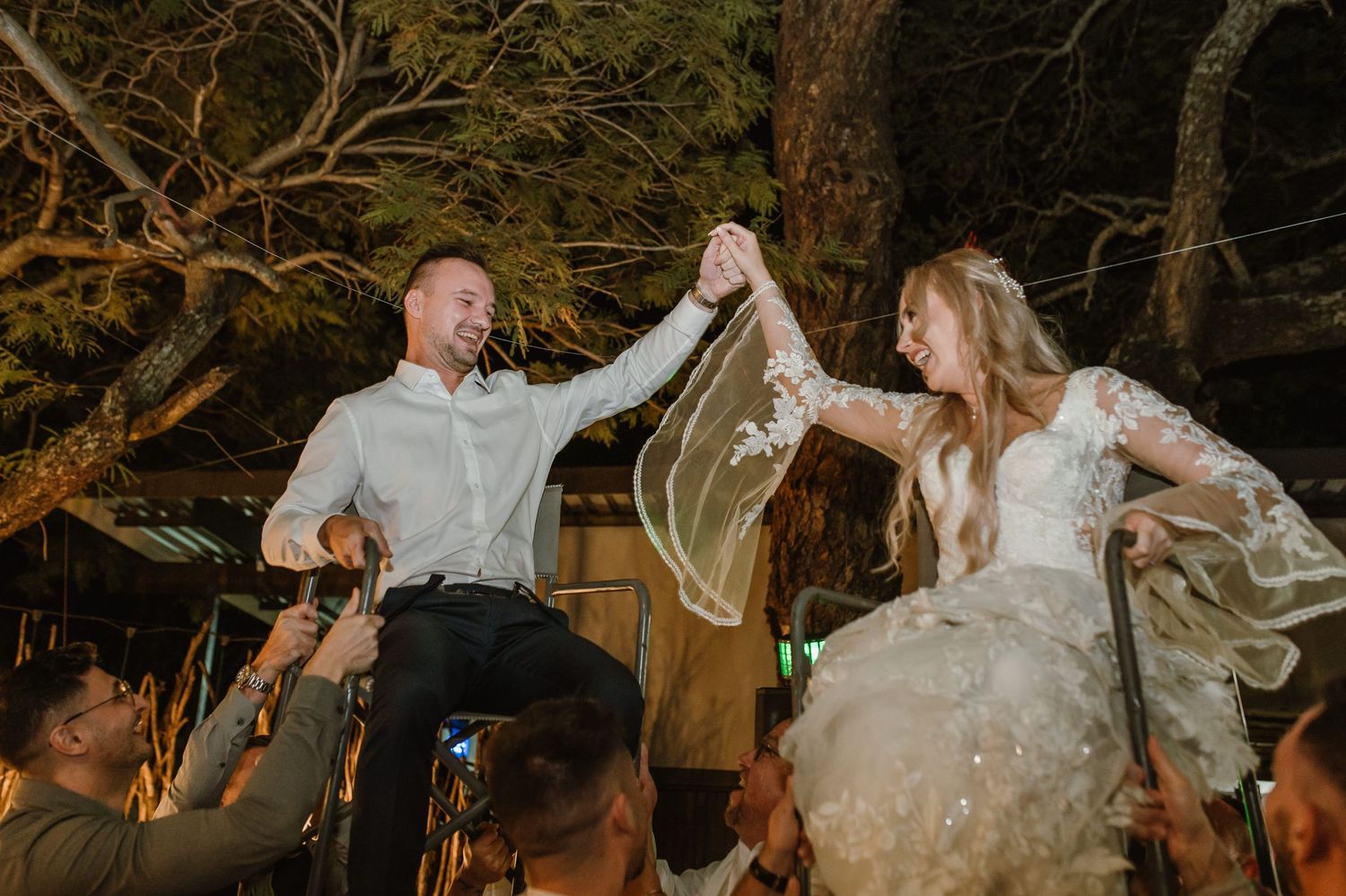 Wedding couple dances joyfully during their outdoor reception celebration at sunset.