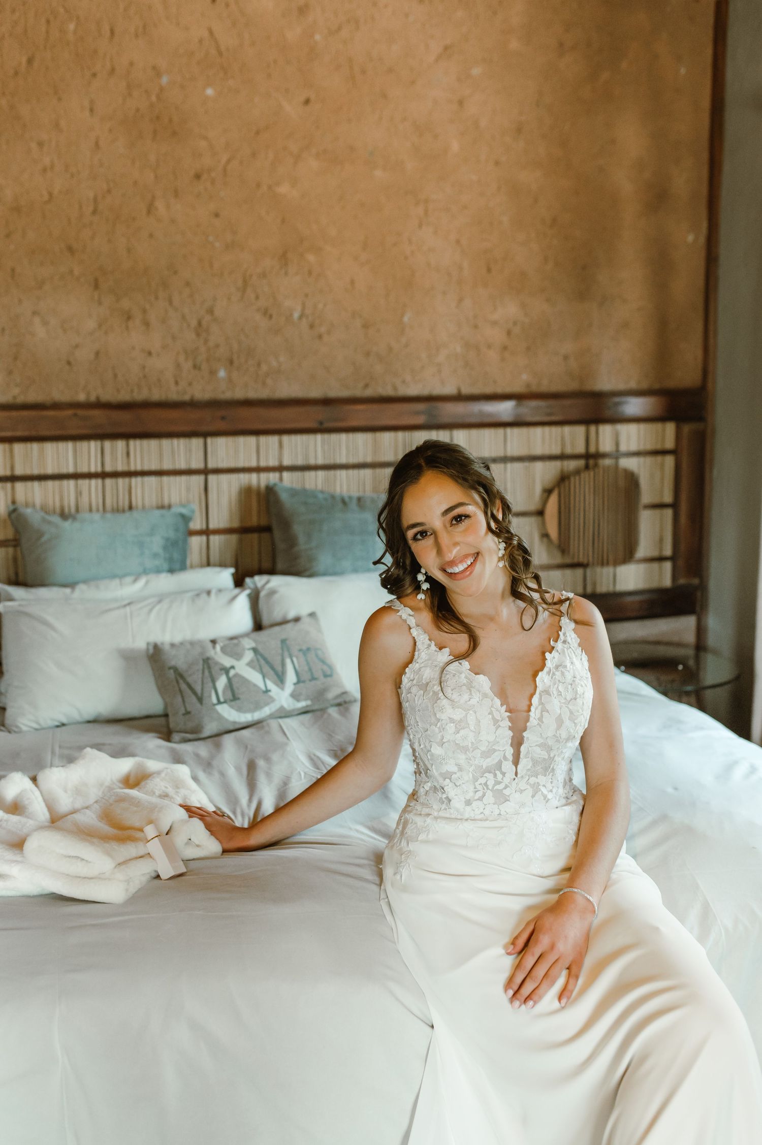 Elegant white lace wedding dress displayed on a bed with decorative details.