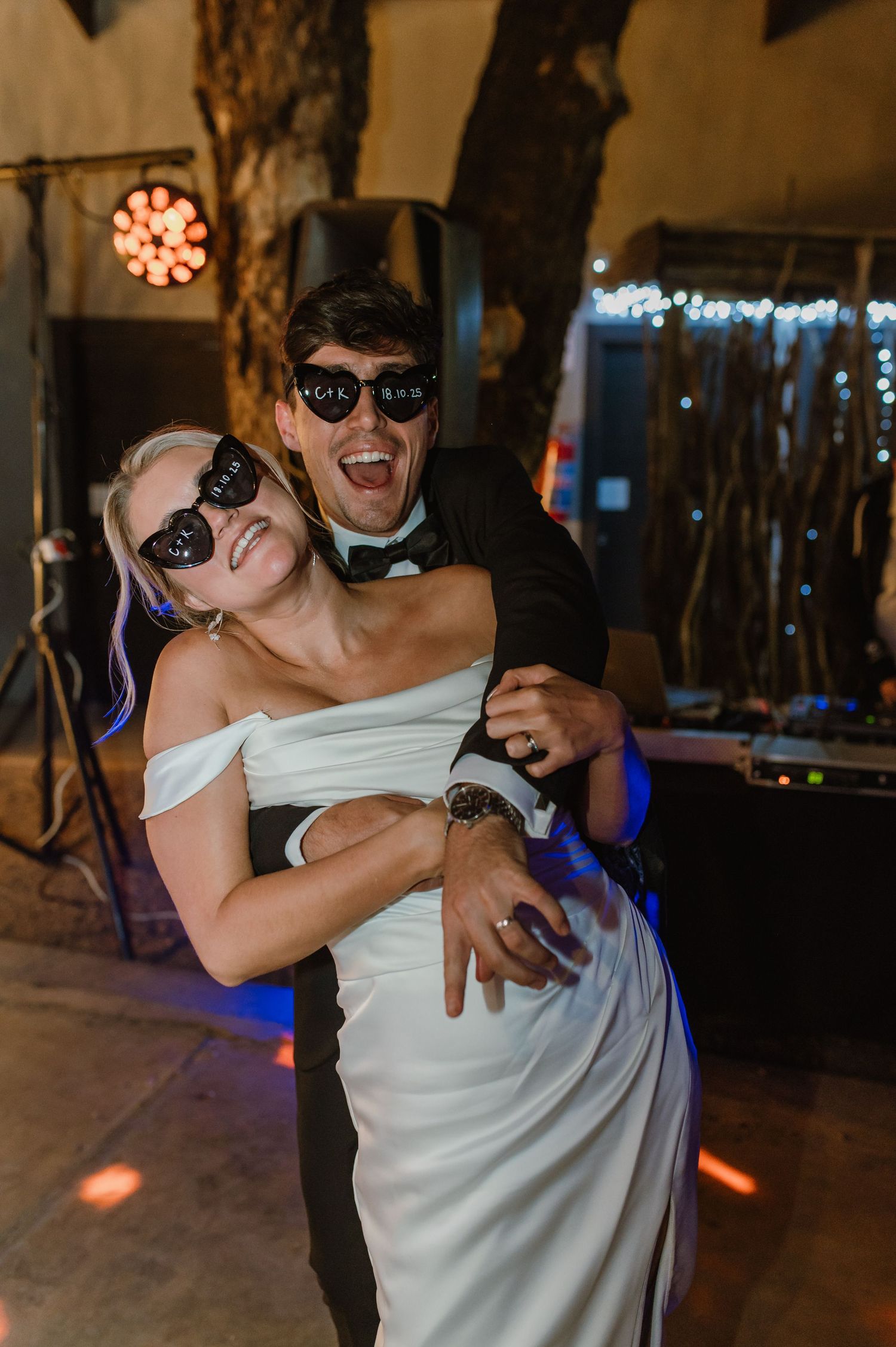 Wedding guests dancing and celebrating with dramatic lighting effects at an evening reception.