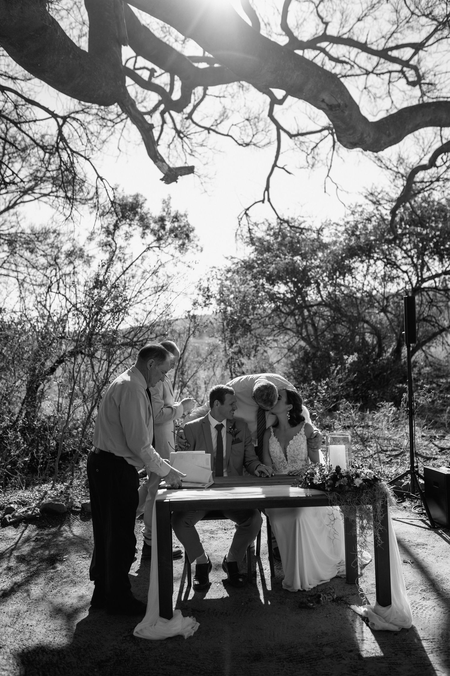 Silhouetted wedding ceremony scene under dramatic desert tree branches.