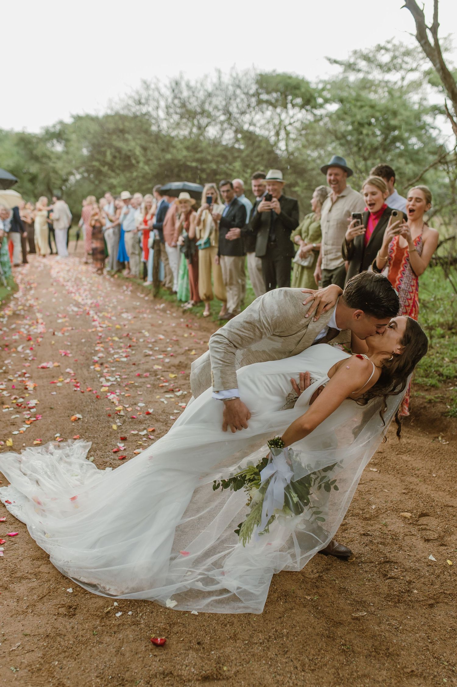 Romantic dip pose during wedding celebration with flower petals falling.