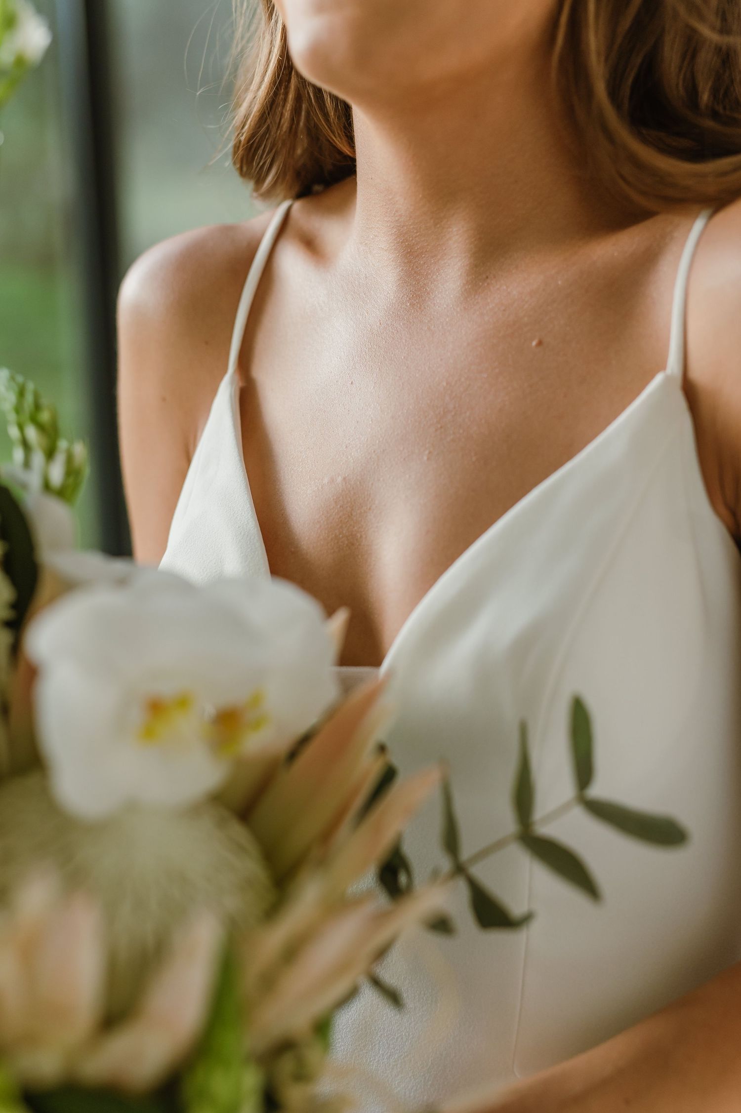 Close-up detail of a white wedding dress with floral elements in the foreground.