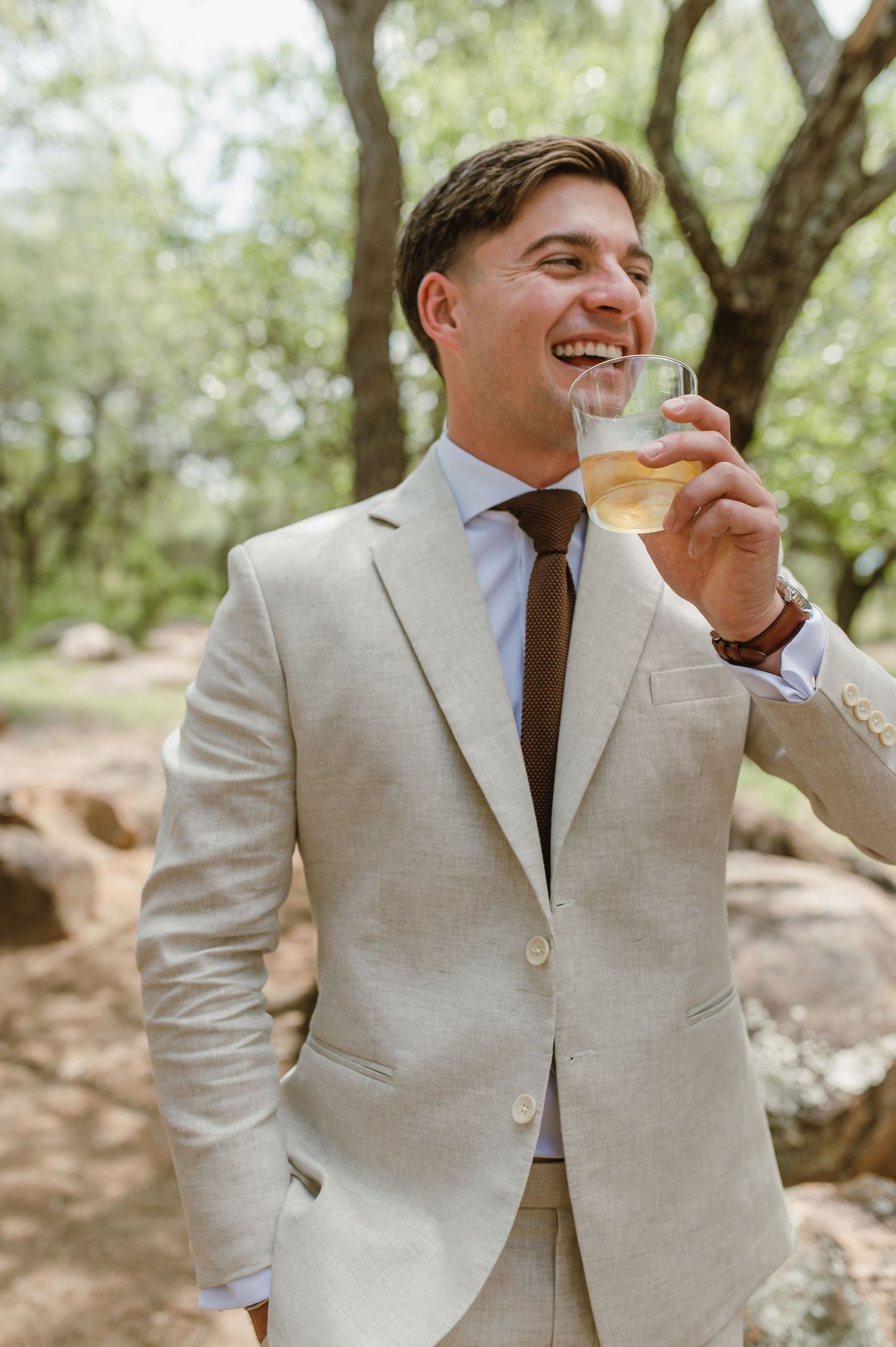 Candid moments of joy captured as groomsmen in beige suits celebrate outdoors.