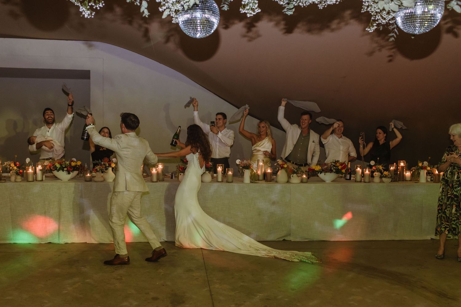 Wedding reception dance floor comes alive with disco balls and string lights overhead.