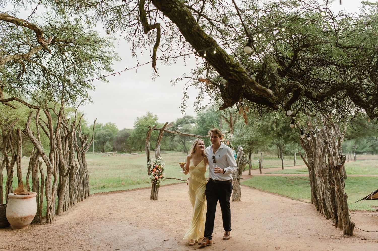 A tree-lined pathway at an outdoor venue with guests walking in the distance.