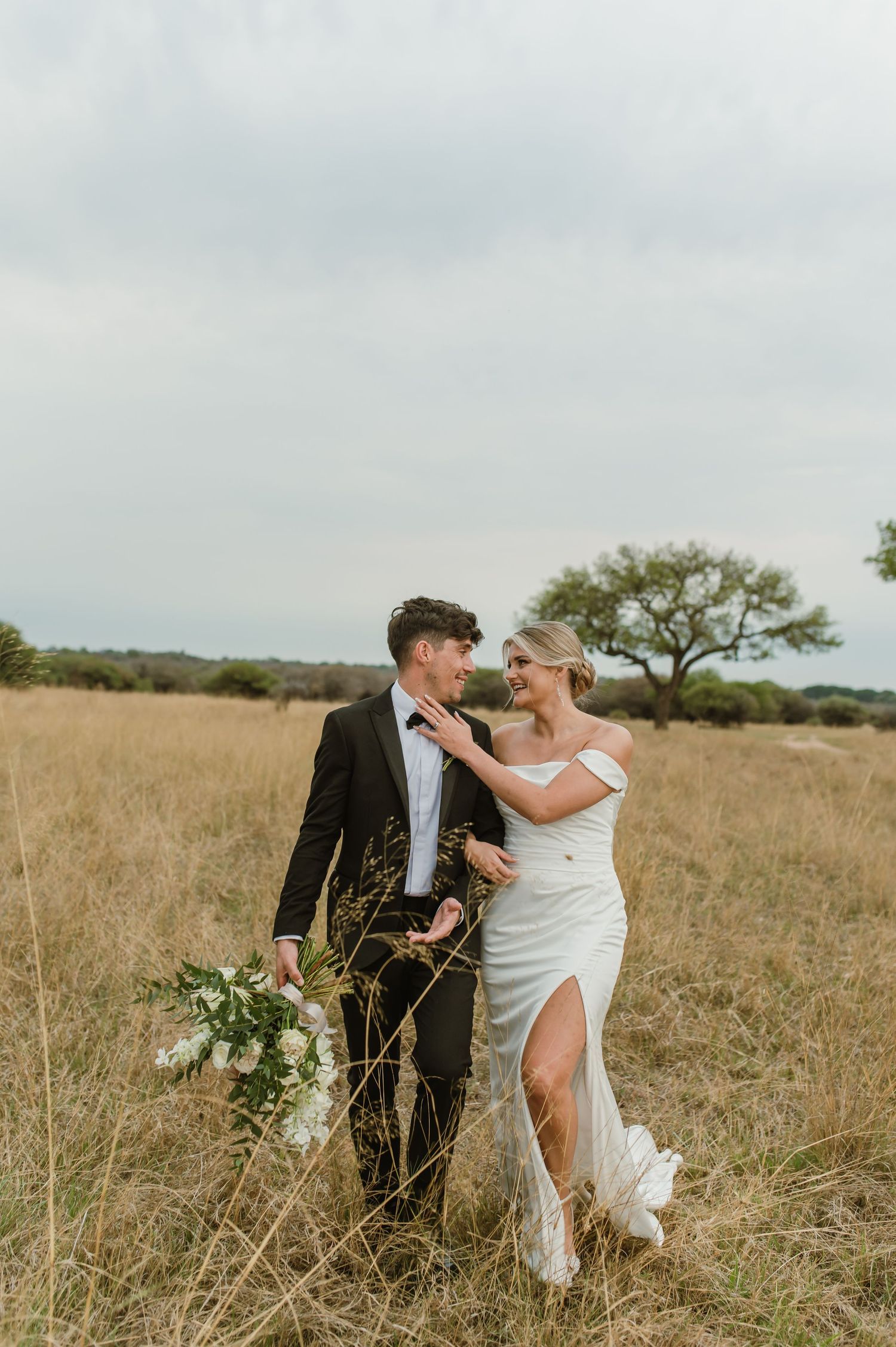 A couple shares a romantic moment in a golden field during their wedding photoshoot.