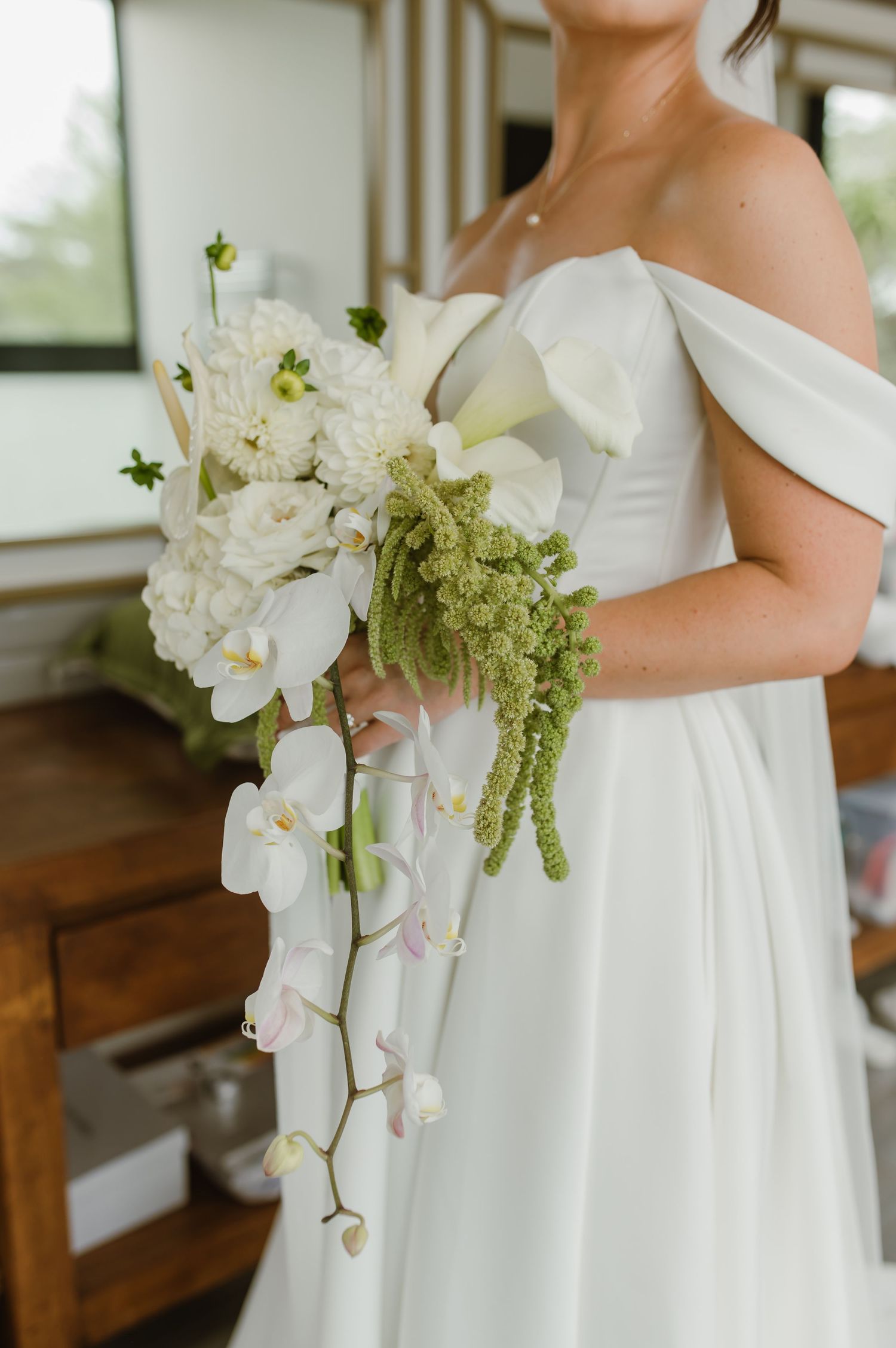 Elegant white wedding dress with cascading orchid bouquet details.