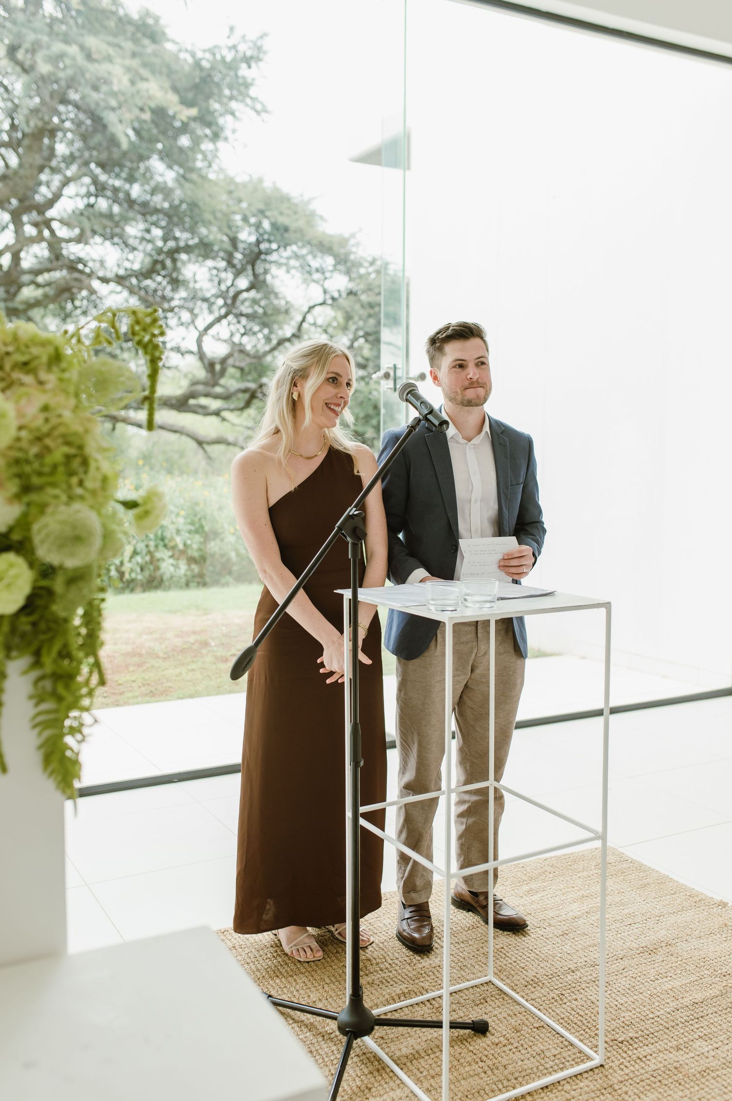 Elegant indoor event space with white decor and glass windows overlooking natural scenery.