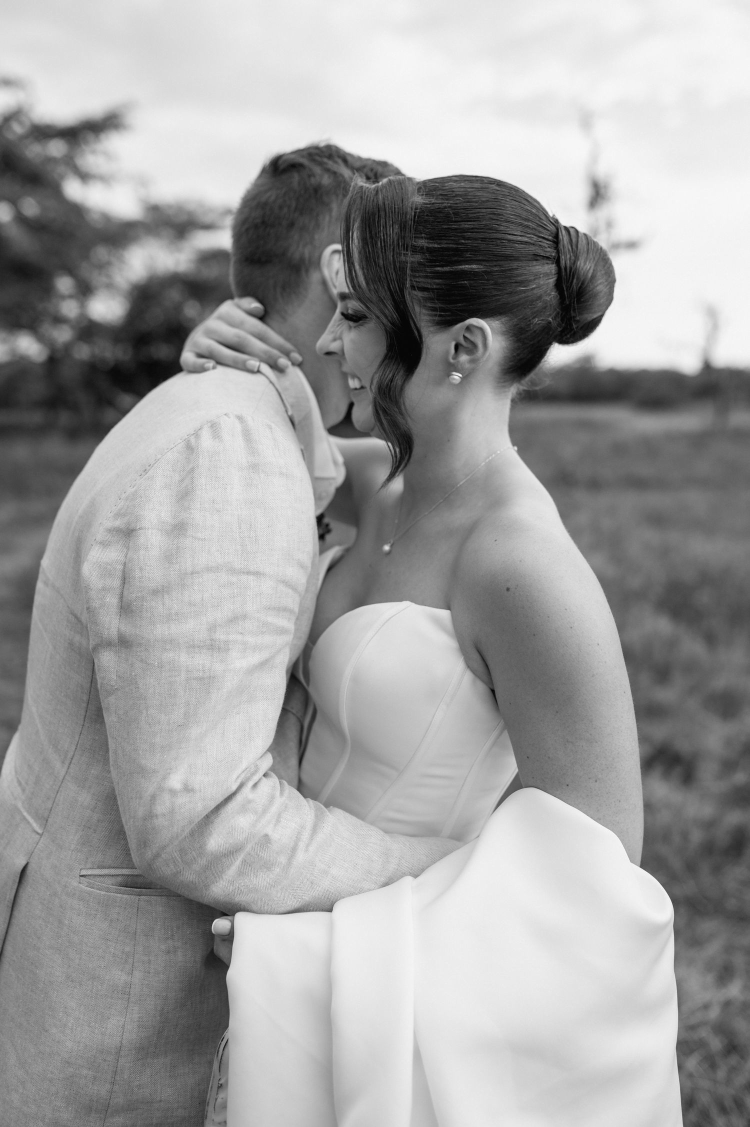 Black and white photo series of a romantic moment between newlyweds in an outdoor field.