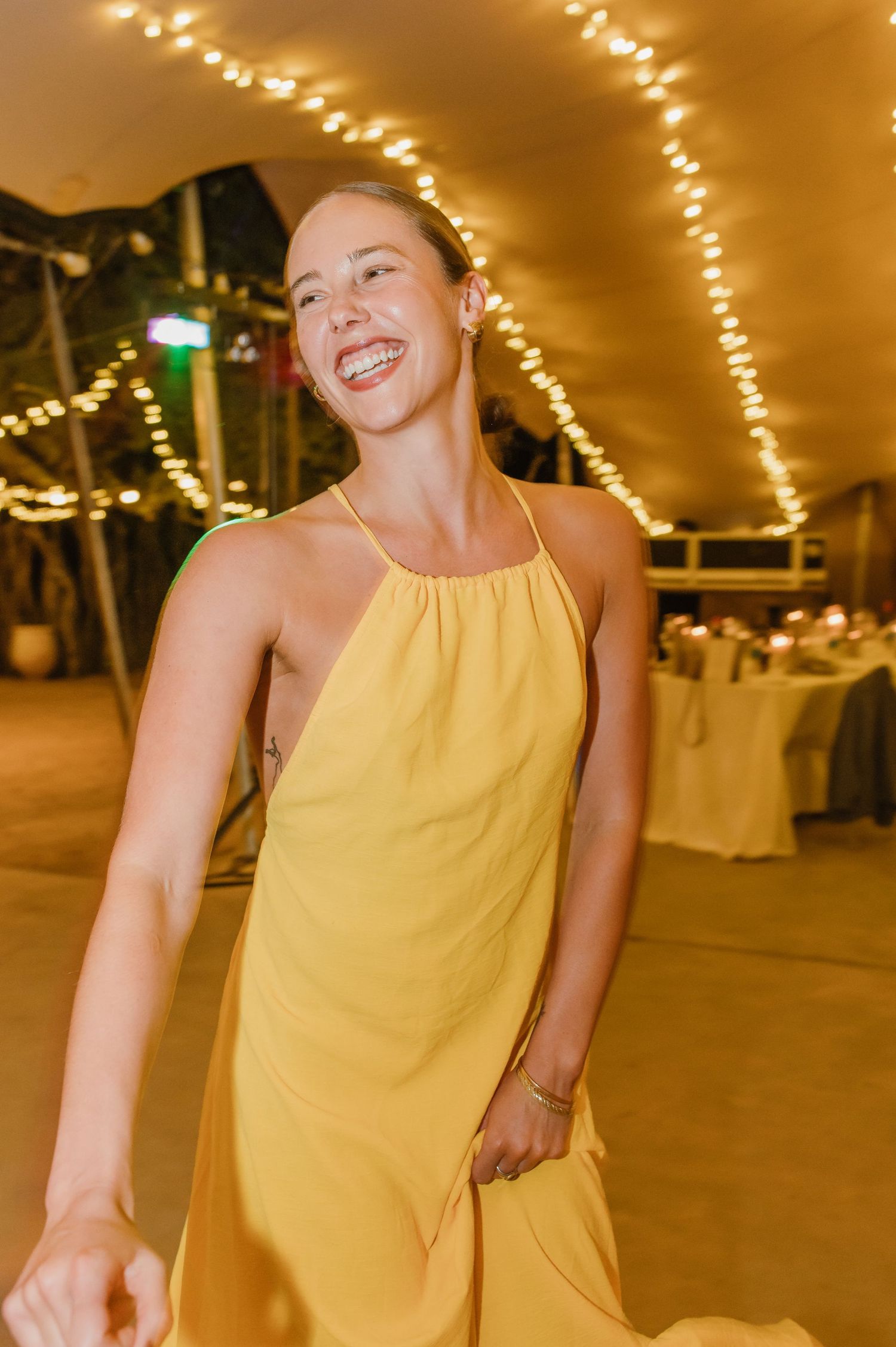 Guest in yellow dress enjoying the wedding reception dance floor.