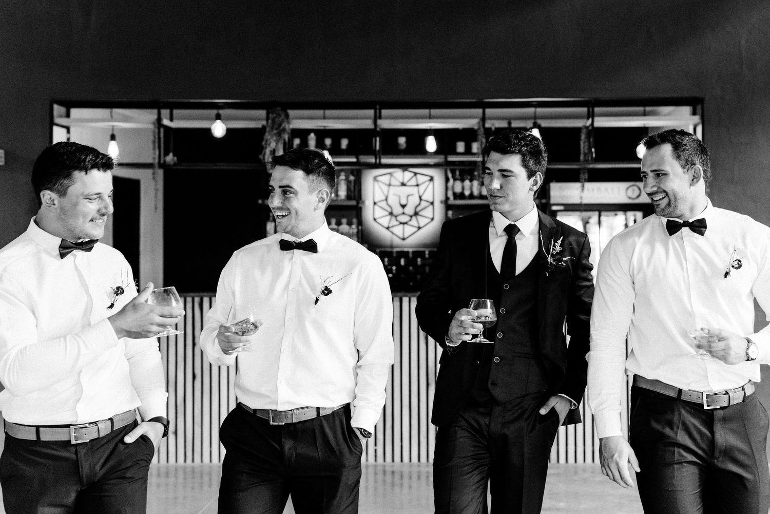 Black and white photo of wedding party members in formal attire at venue.