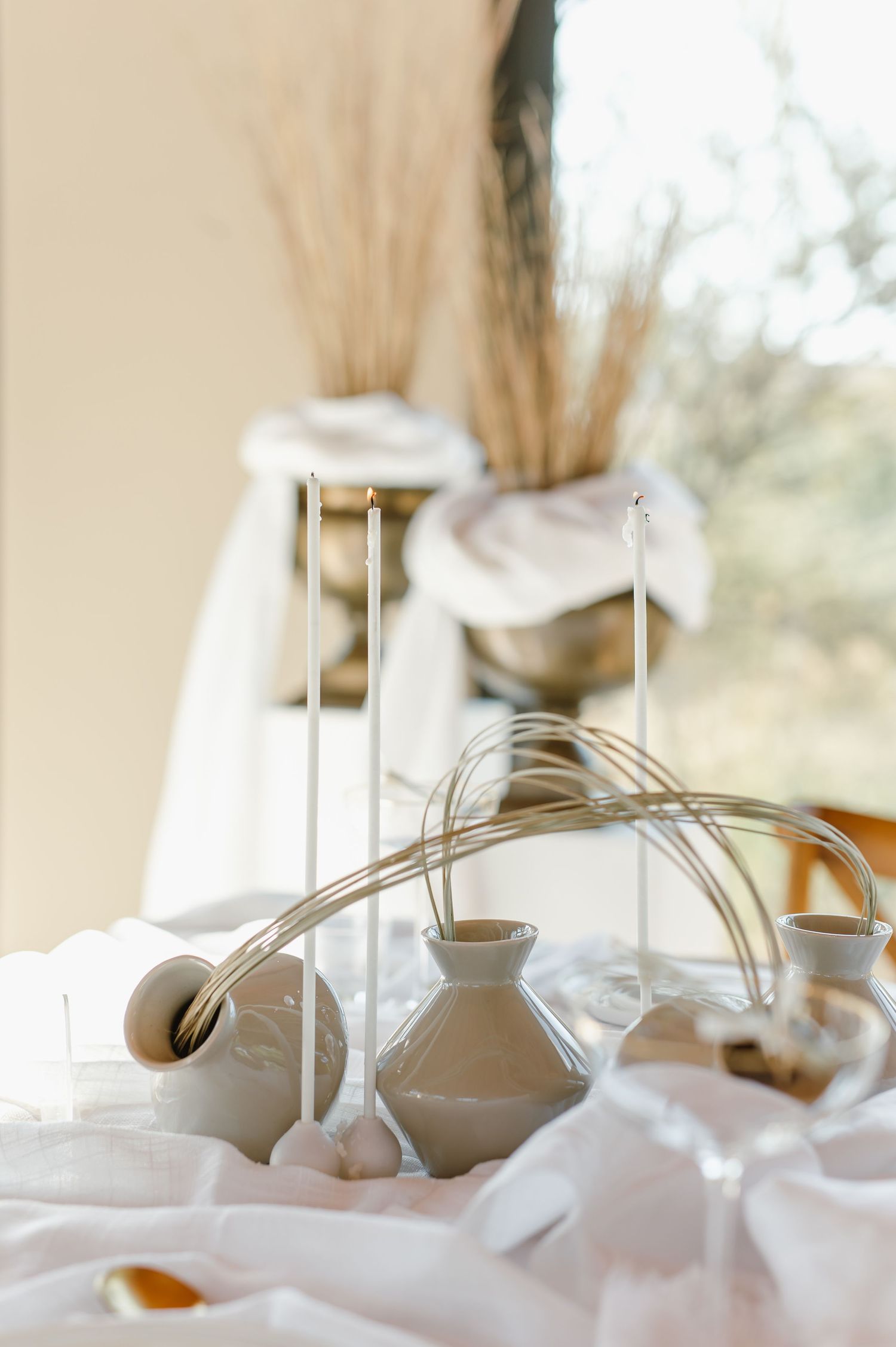 Soft focus wedding decor with delicate vases and dried flowers in natural light.