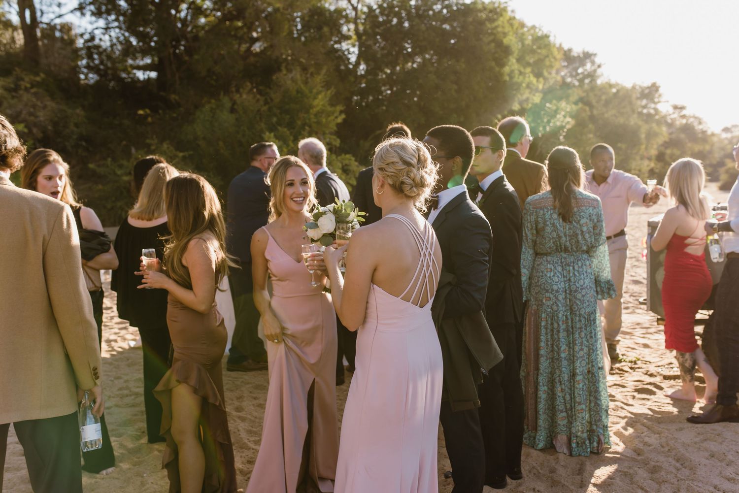 Guests enjoying a beach wedding reception during golden hour with beautiful natural lighting.