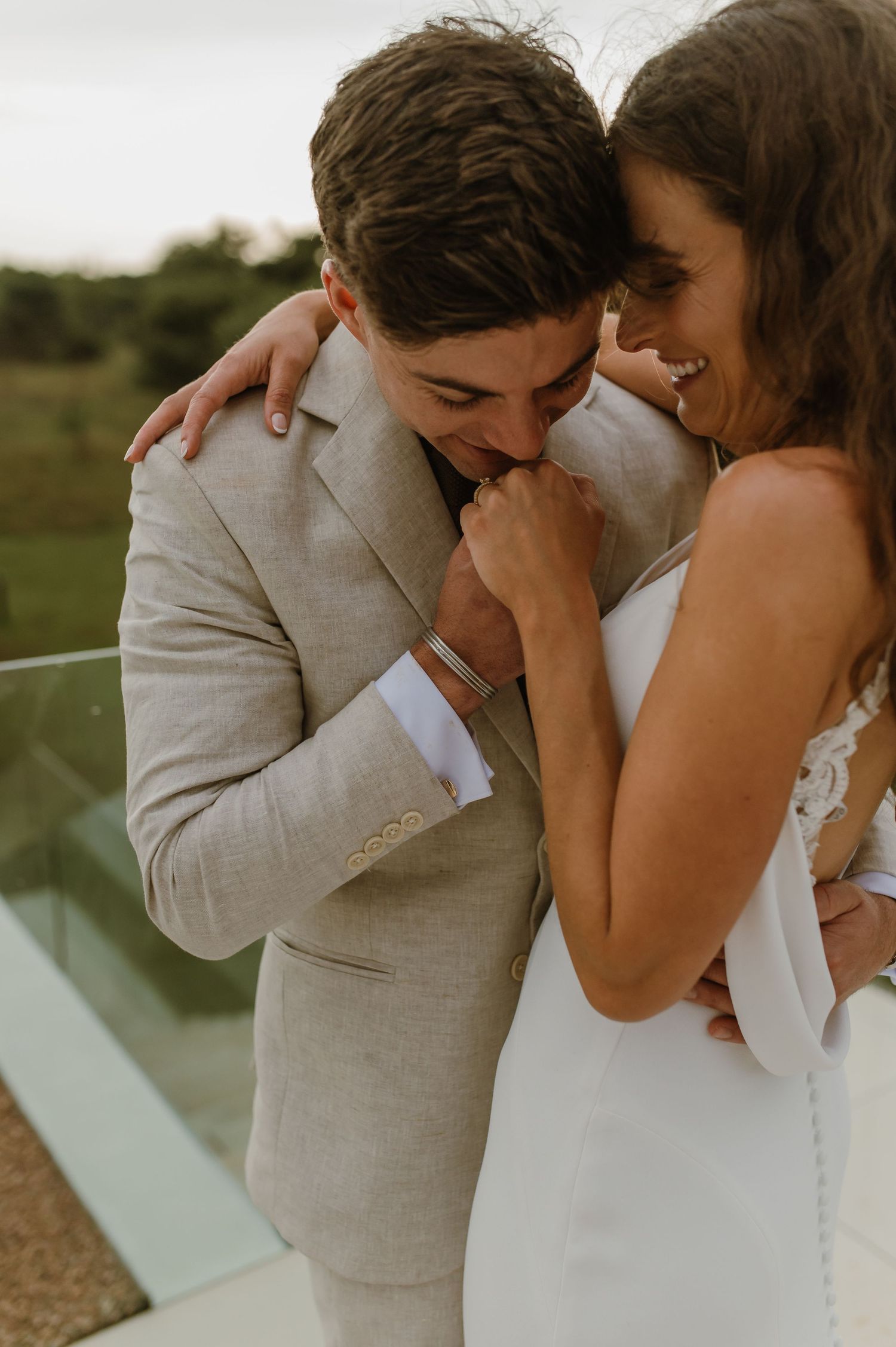 Intimate moment between newlyweds sharing laughter on a modern balcony.