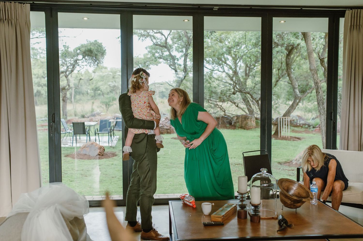 Wedding party gathering in a modern room with large windows overlooking nature.
