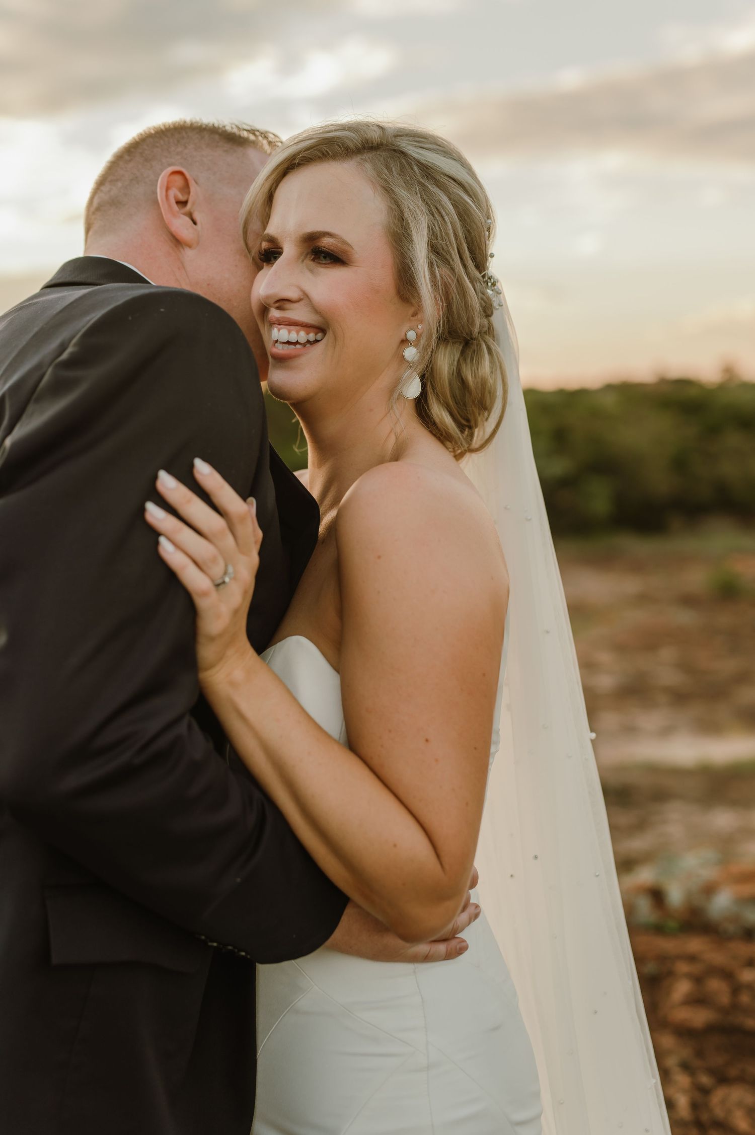 Wedding couple shares tender moments against a warm sunset sky in a desert landscape.