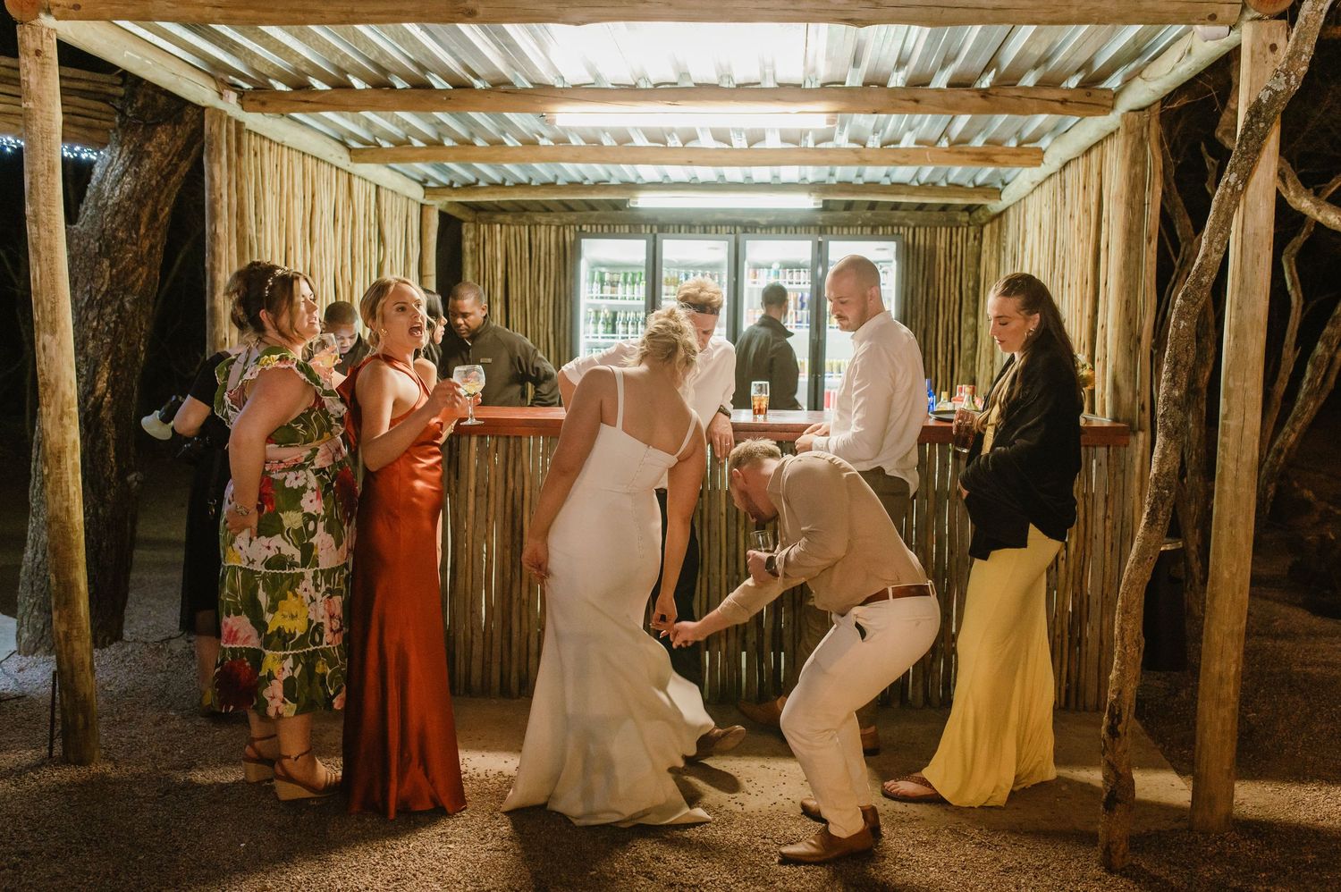 Wedding party dances and celebrates in a rustic wooden venue with natural light streaming in.