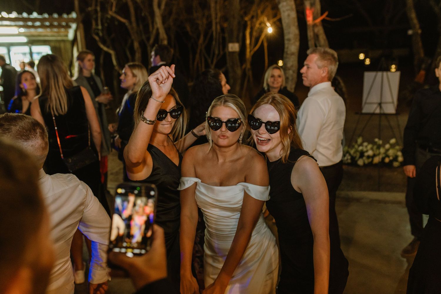 Wedding guests dance and celebrate at an evening reception with warm lighting and festive atmosphere.