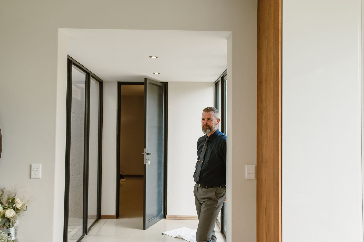 Modern minimalist hallway with wooden accents and white walls in a wedding venue.