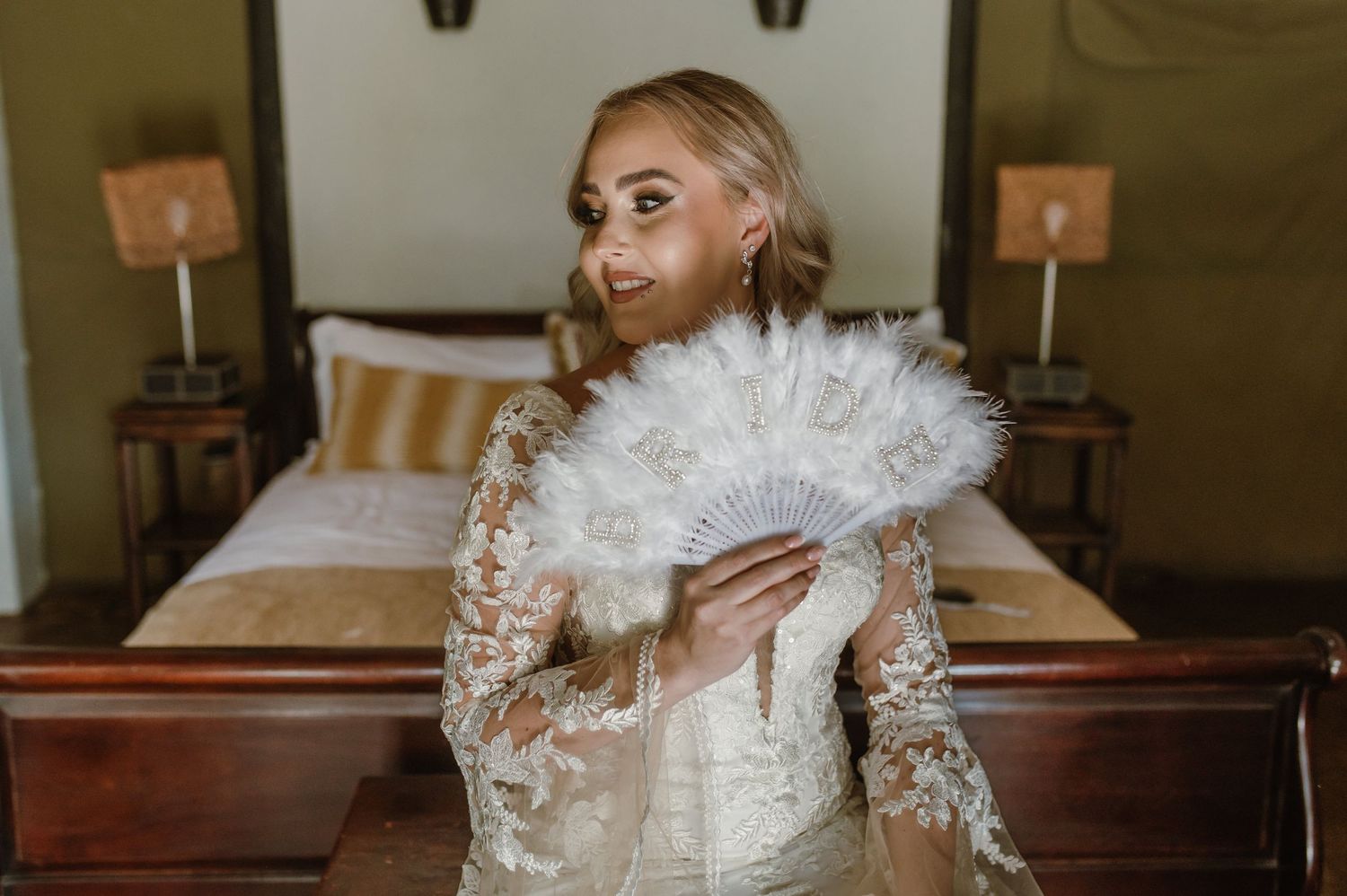 A close-up shot of a bride holding a white feather fan against her wedding gown.