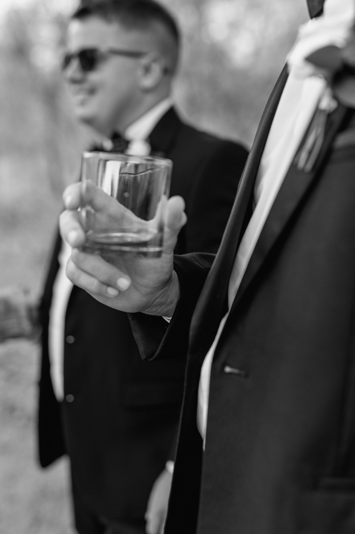 Close-up shots of hands holding drinks during formal wedding celebration.