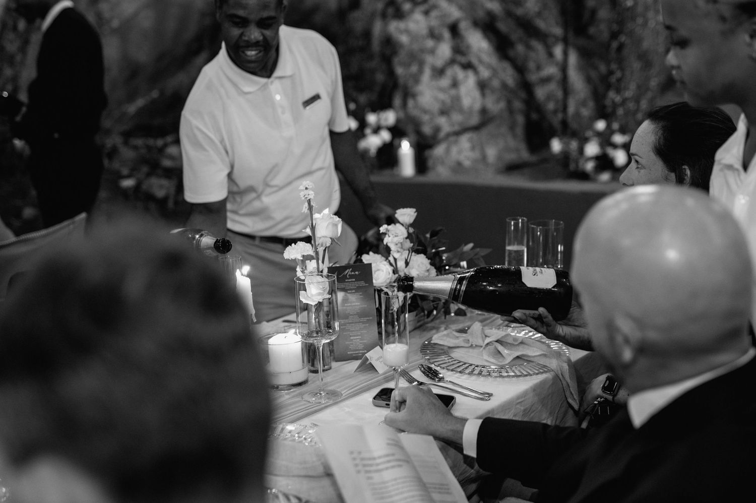 Wedding reception dinner with guests seated at tables under ambient lighting.