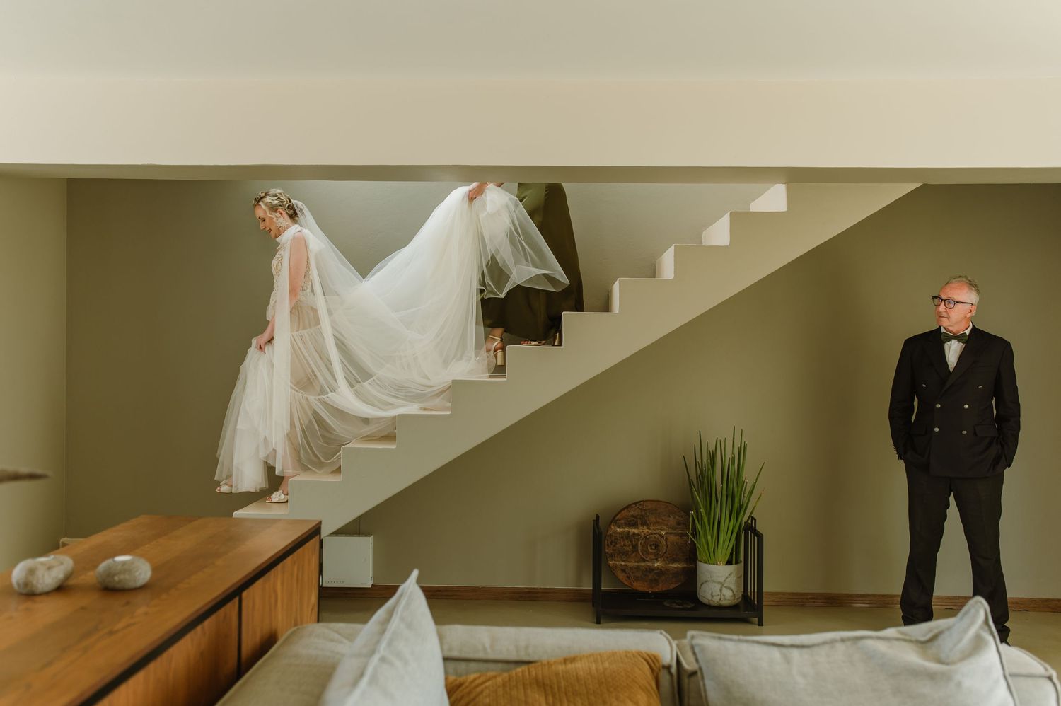 Elegant wedding party descending modern white staircase.