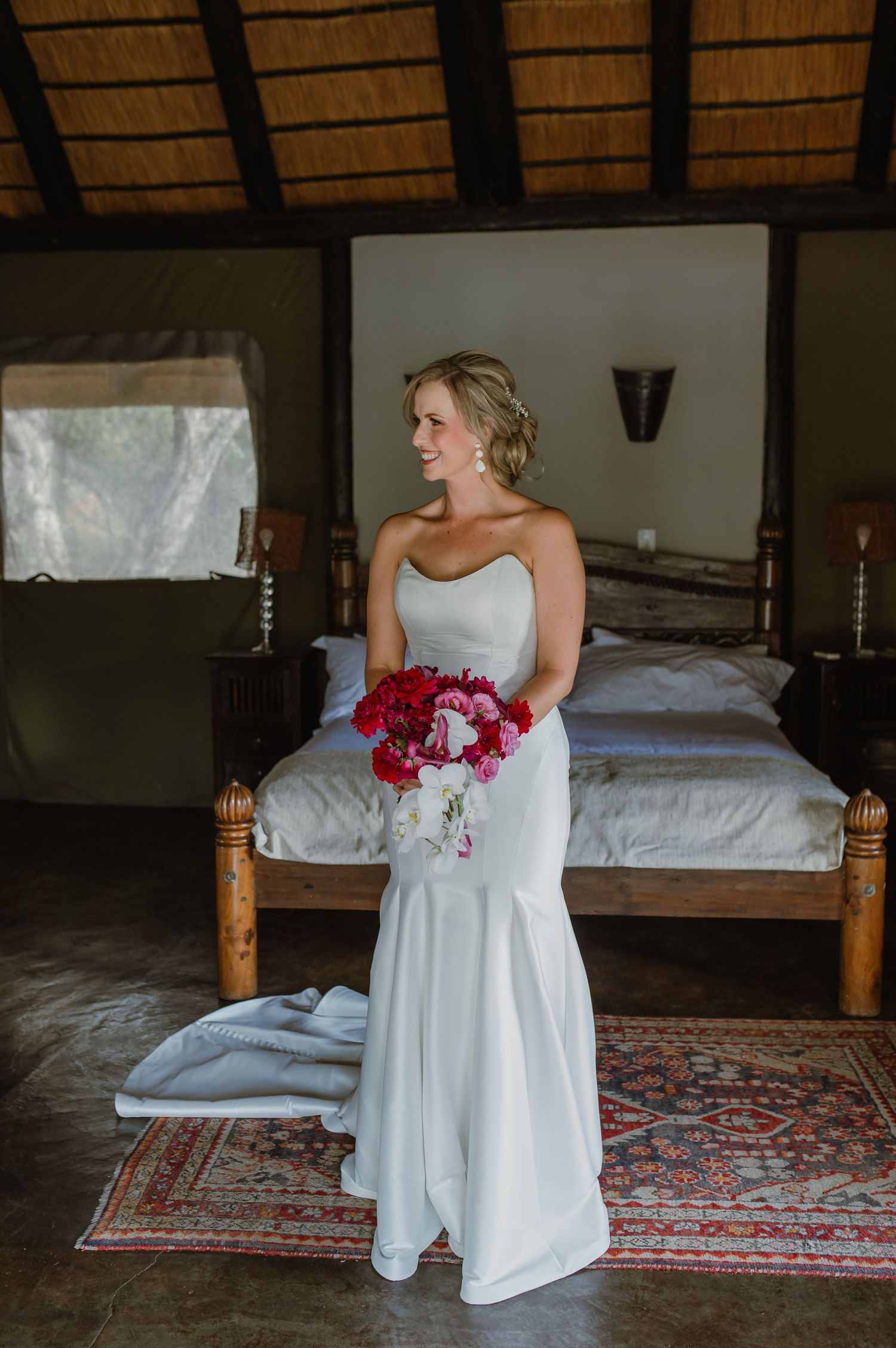 Wedding dress and bouquet details in a rustic room with wooden beams and patterned carpet.