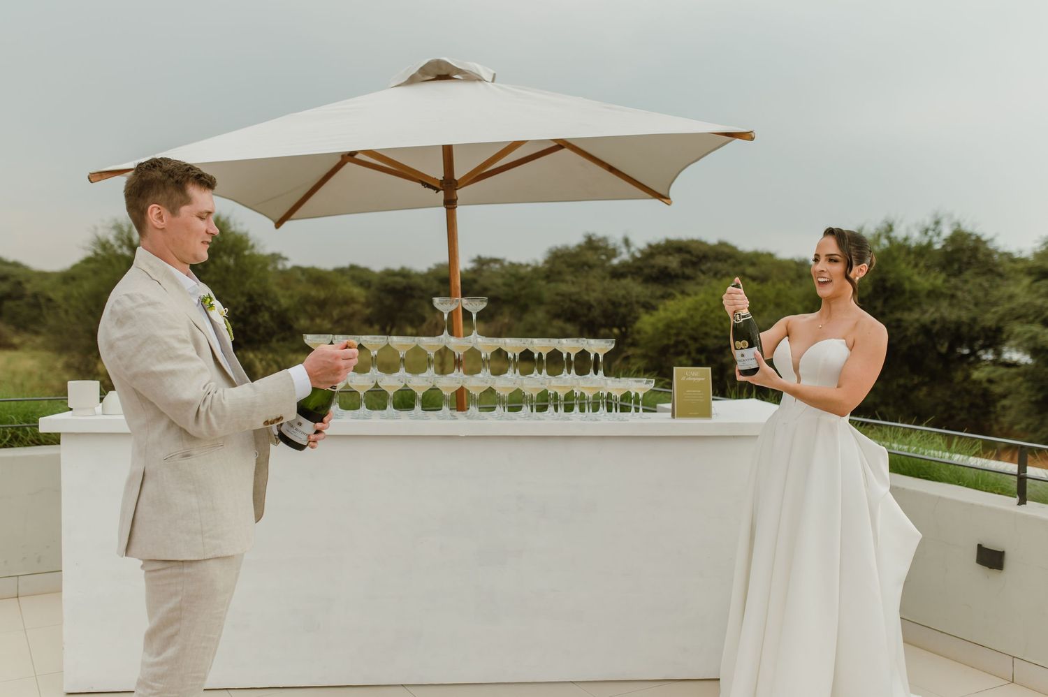 A couple shares a romantic moment under a white umbrella on an elegant outdoor terrace.