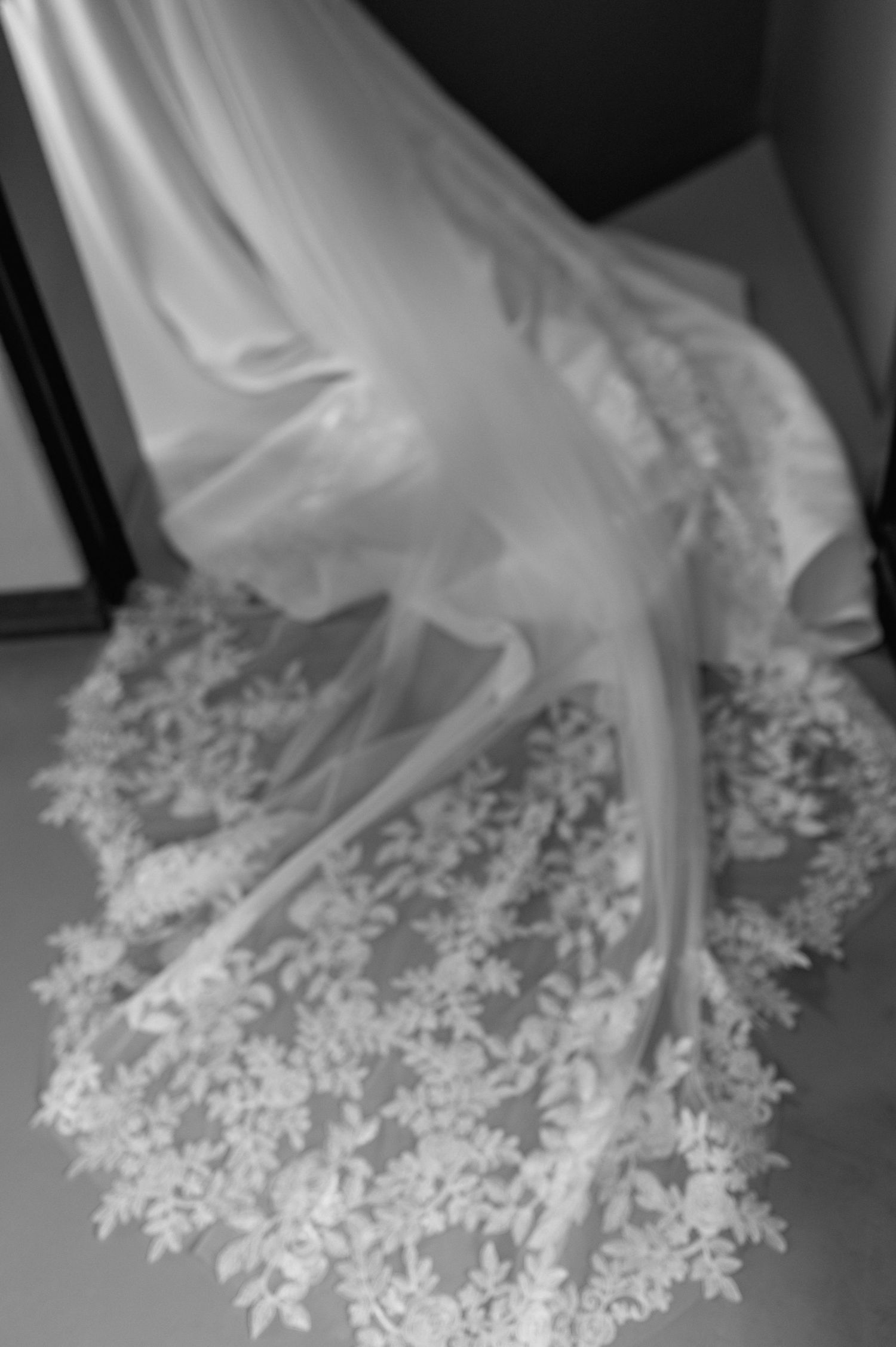 A sequence of black and white photos showing a delicate white fabric with lace details gradually fading into darkness.