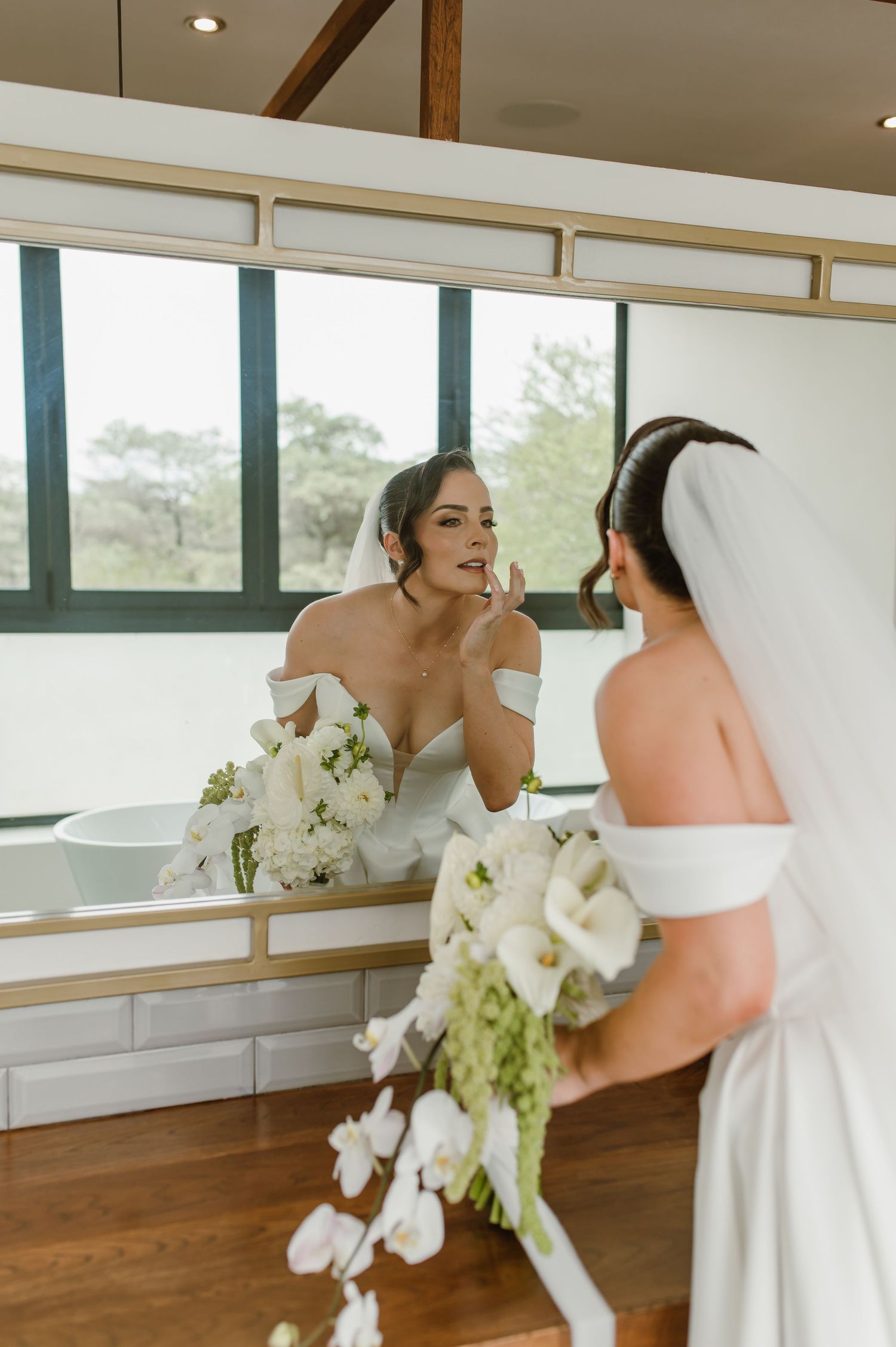 White orchid bouquet being held in an elegant interior space with wooden floors and large windows.
