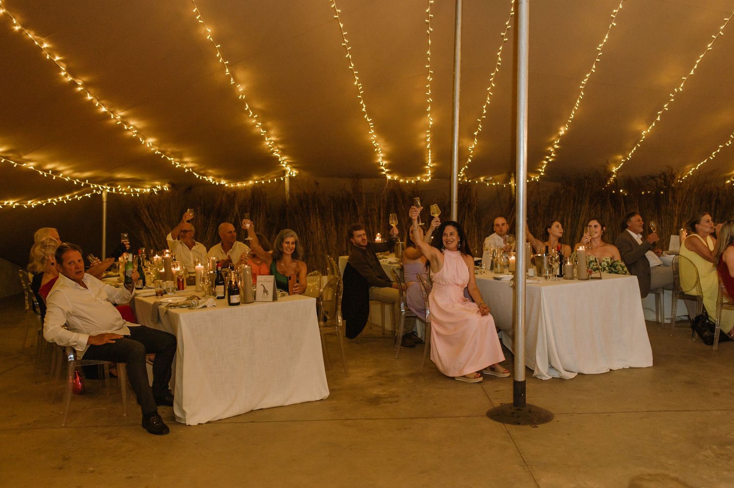 Large wedding reception space with string lights overhead and guests seated at decorated tables.