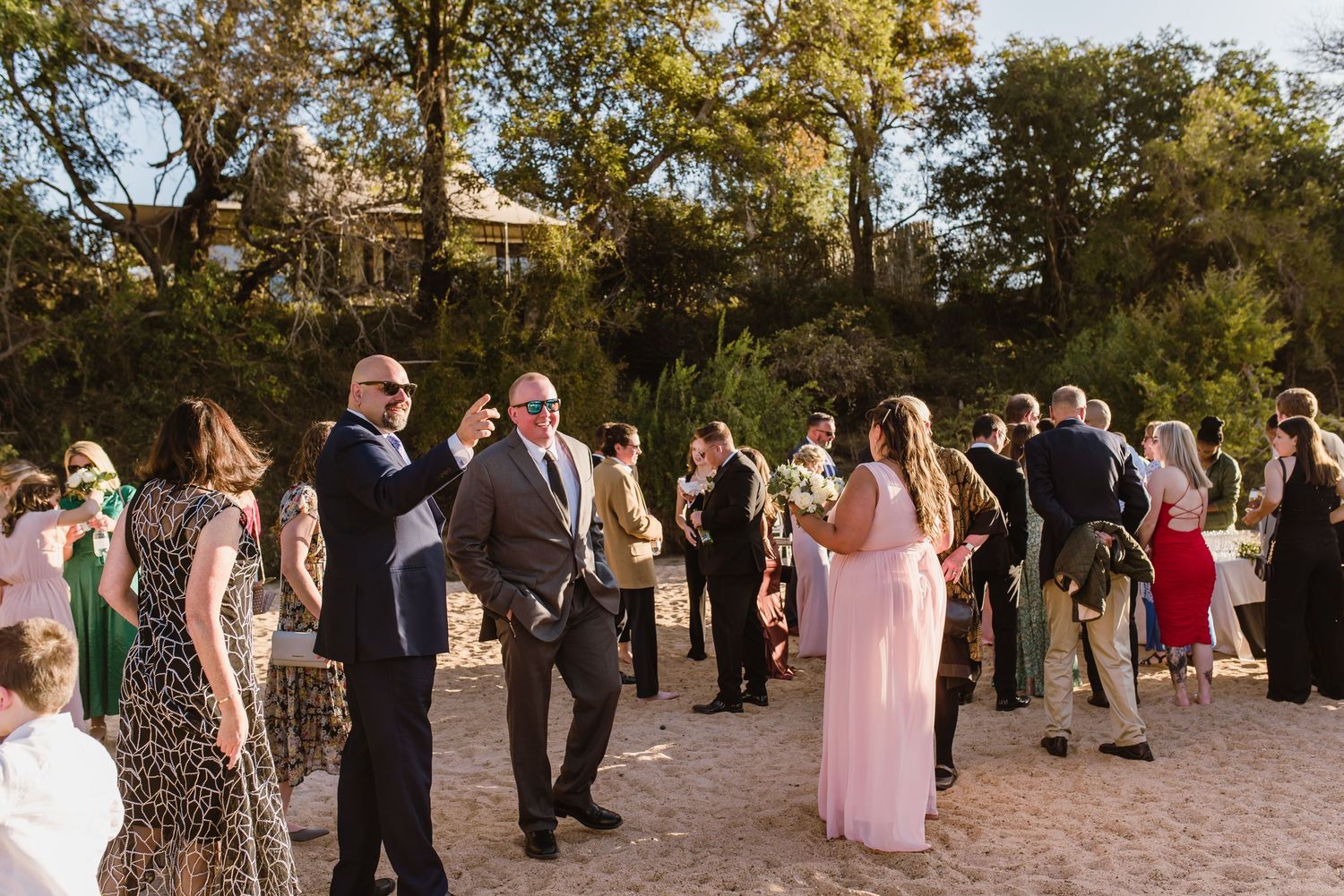 Wedding guests mingle and celebrate during an outdoor reception on a sunny afternoon.