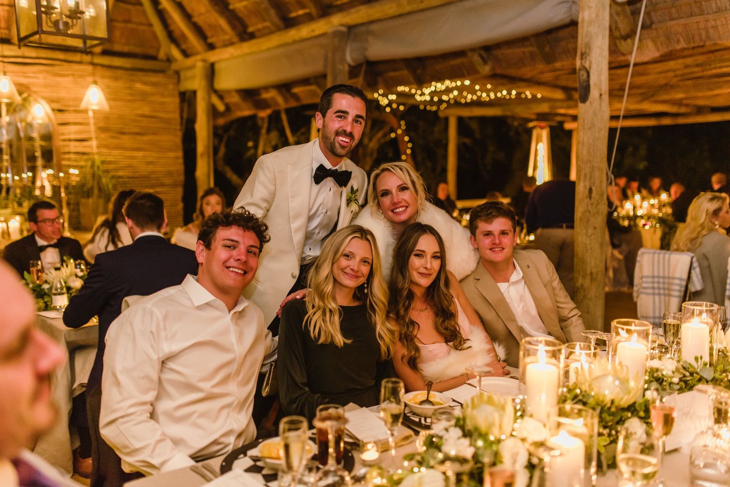 Rustic wooden venue with warm lighting and guests enjoying a wedding reception dinner.