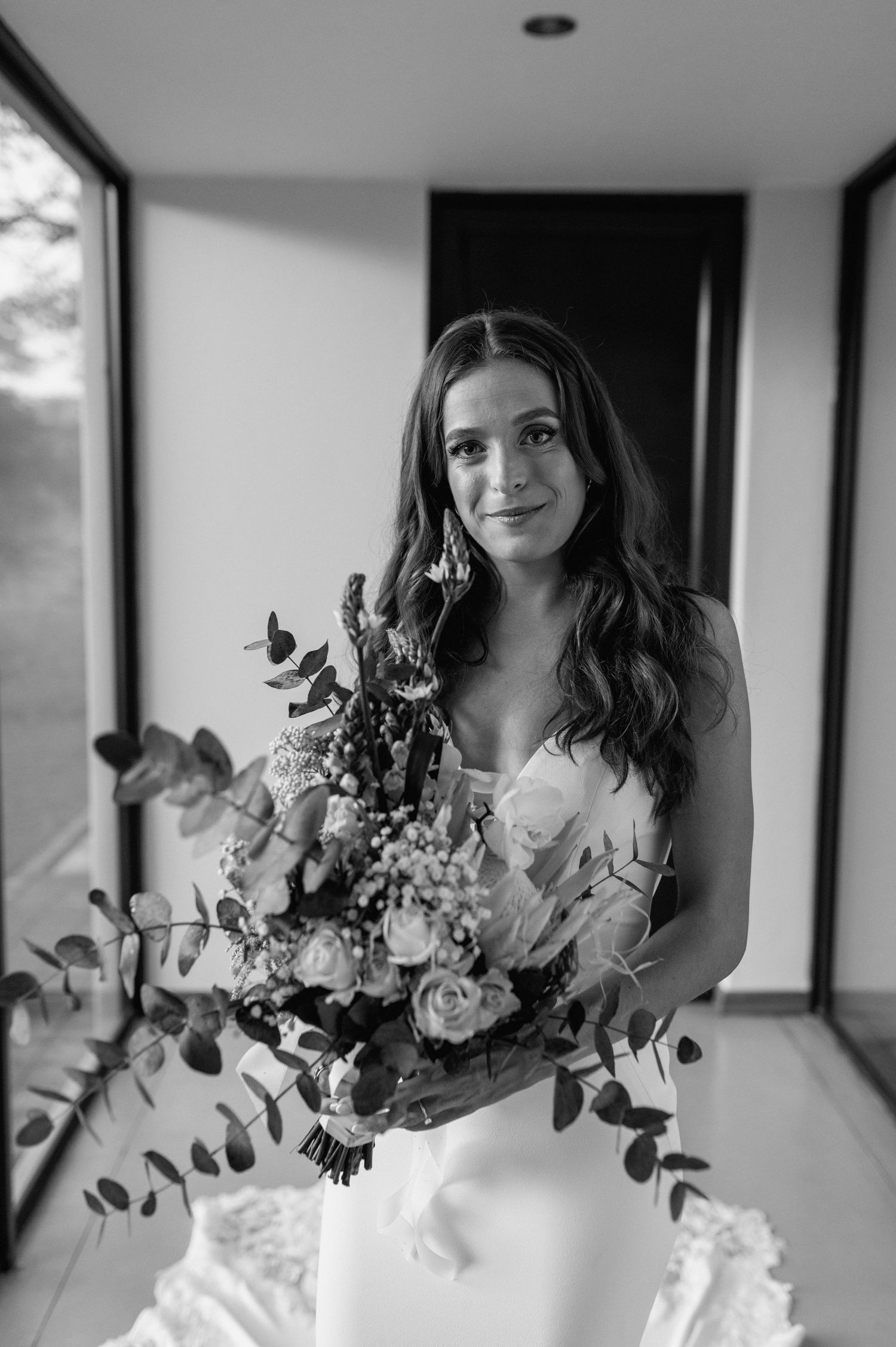 Black and white portrait of someone holding a lush wedding bouquet with eucalyptus.
