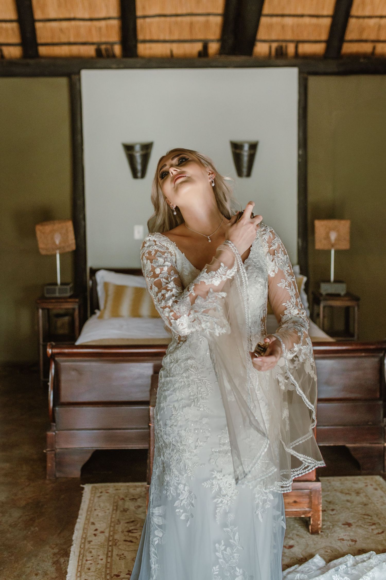 Final adjustments being made to an elegant lace wedding gown in a rustic venue.