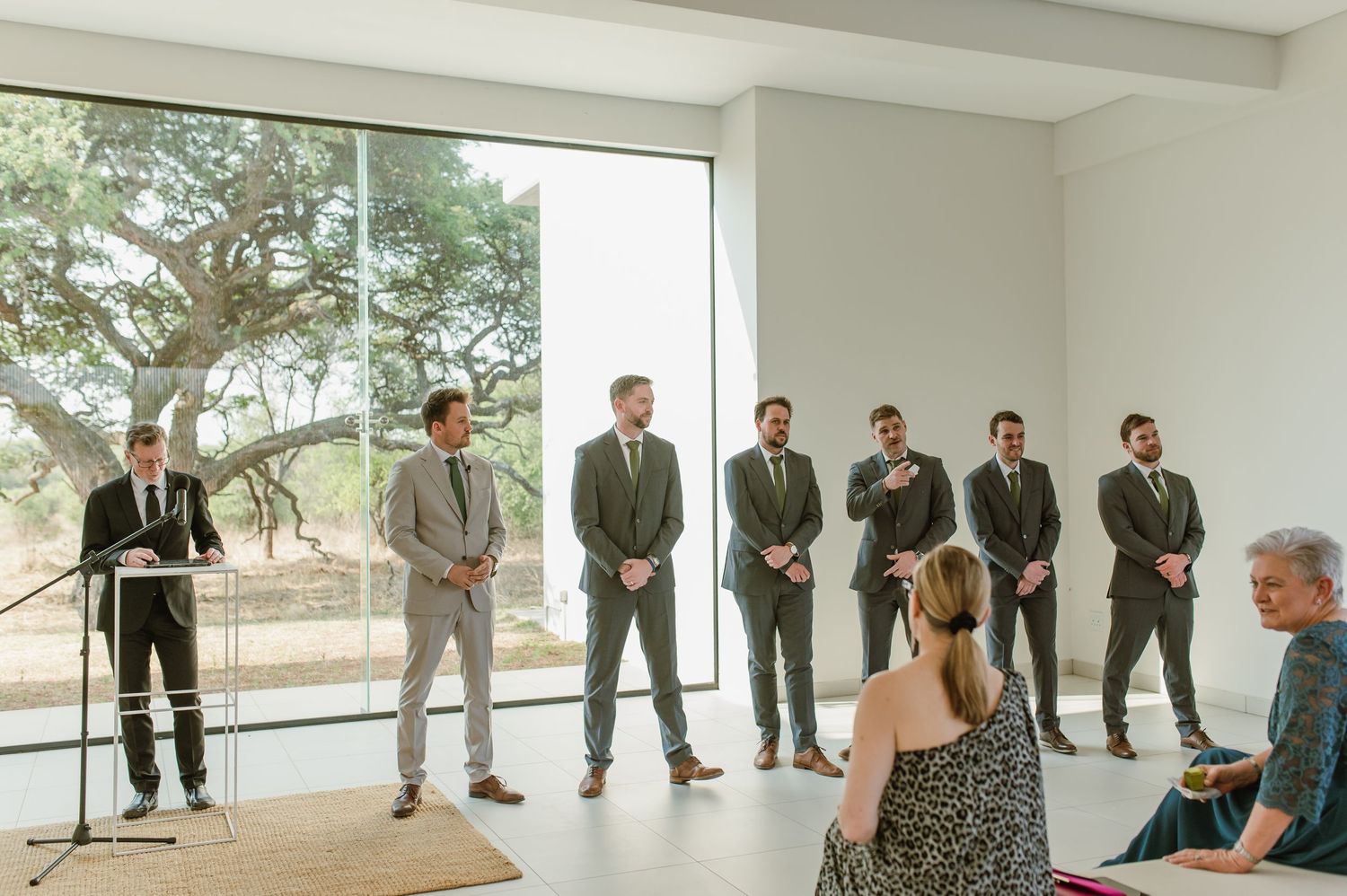 Modern white interior room with large windows and formal event setup.