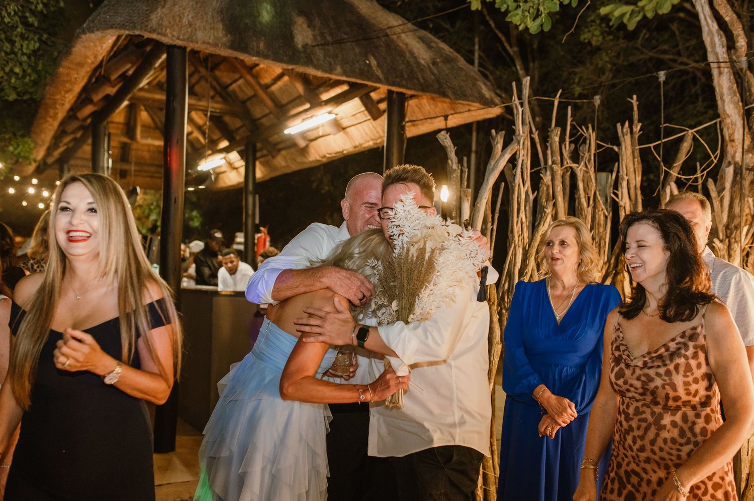 Wedding guests enjoying the dance floor during evening reception under rustic lighting.