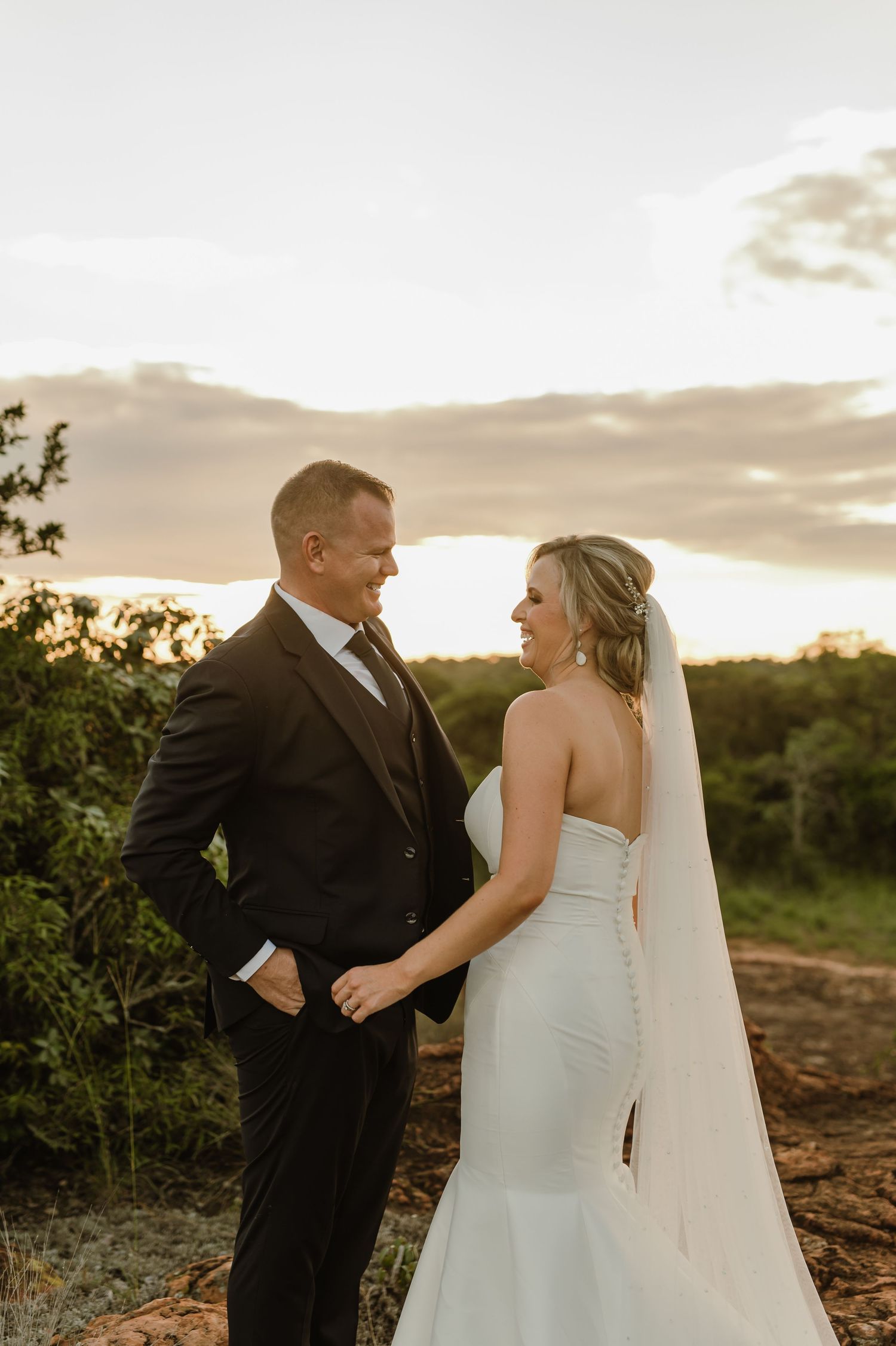 Sunset wedding portraits captured on natural terrain with dramatic sky backdrop.